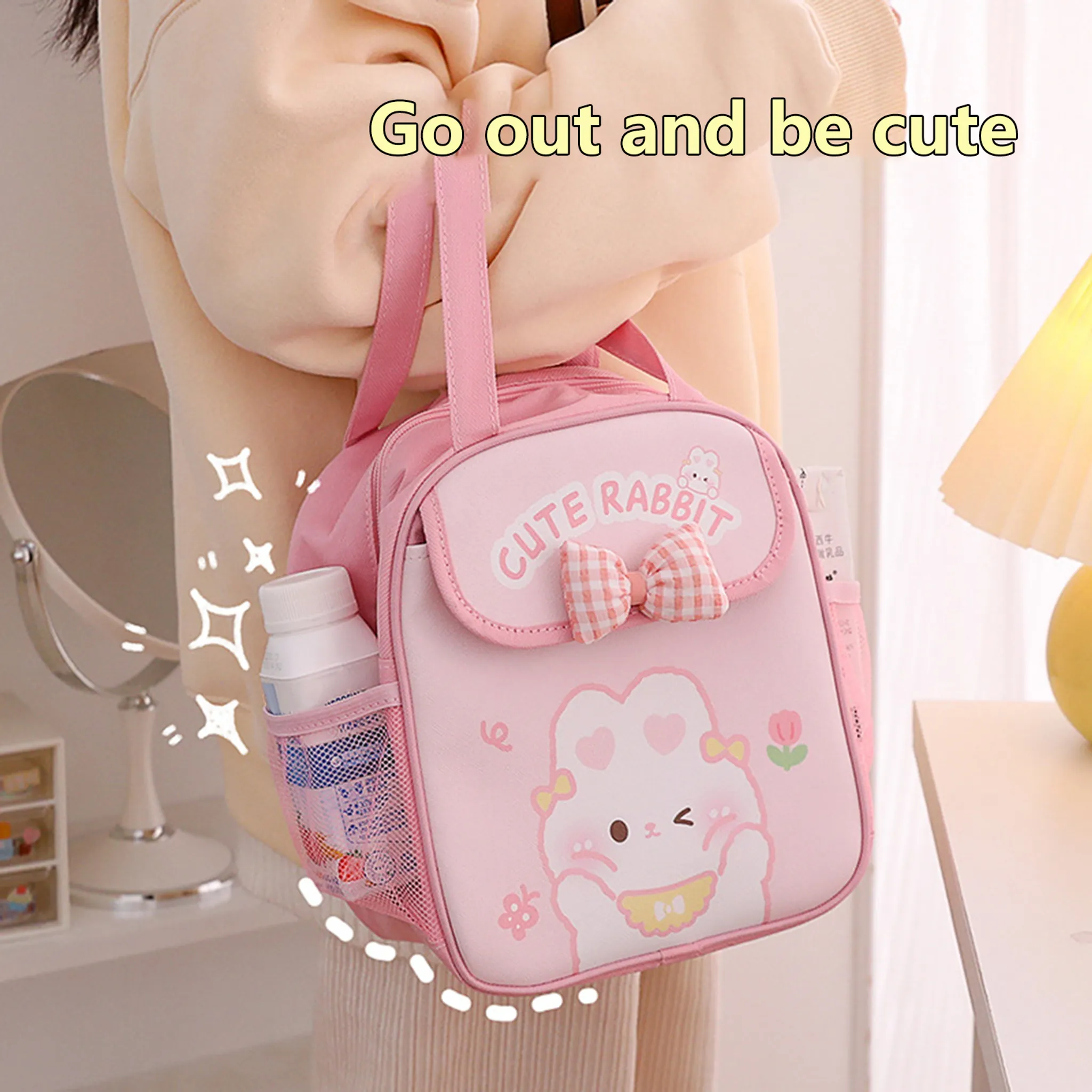Eine Person hält eine rosa Tasche mit Kaninchenmuster. Die Tasche hat eine Schleife und die Worte "CUTE RABBIT". Der Hintergrund ist unscharf.