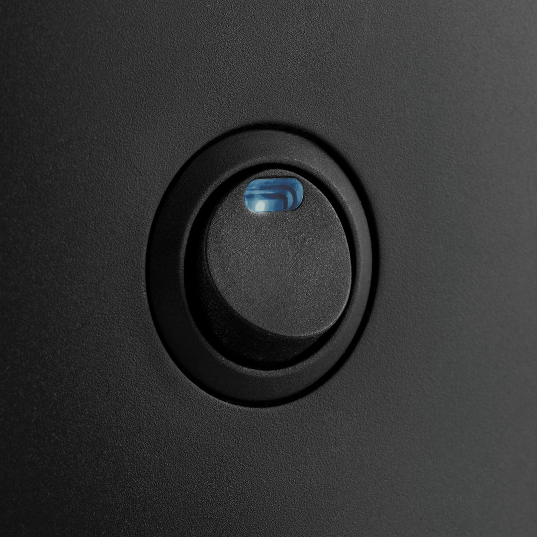 Zbliżenie czarnego przycisku zasilania z niebieskim podświetlanym wskaźnikiem na ciemnej powierzchni. Przycisk jest okrągły.