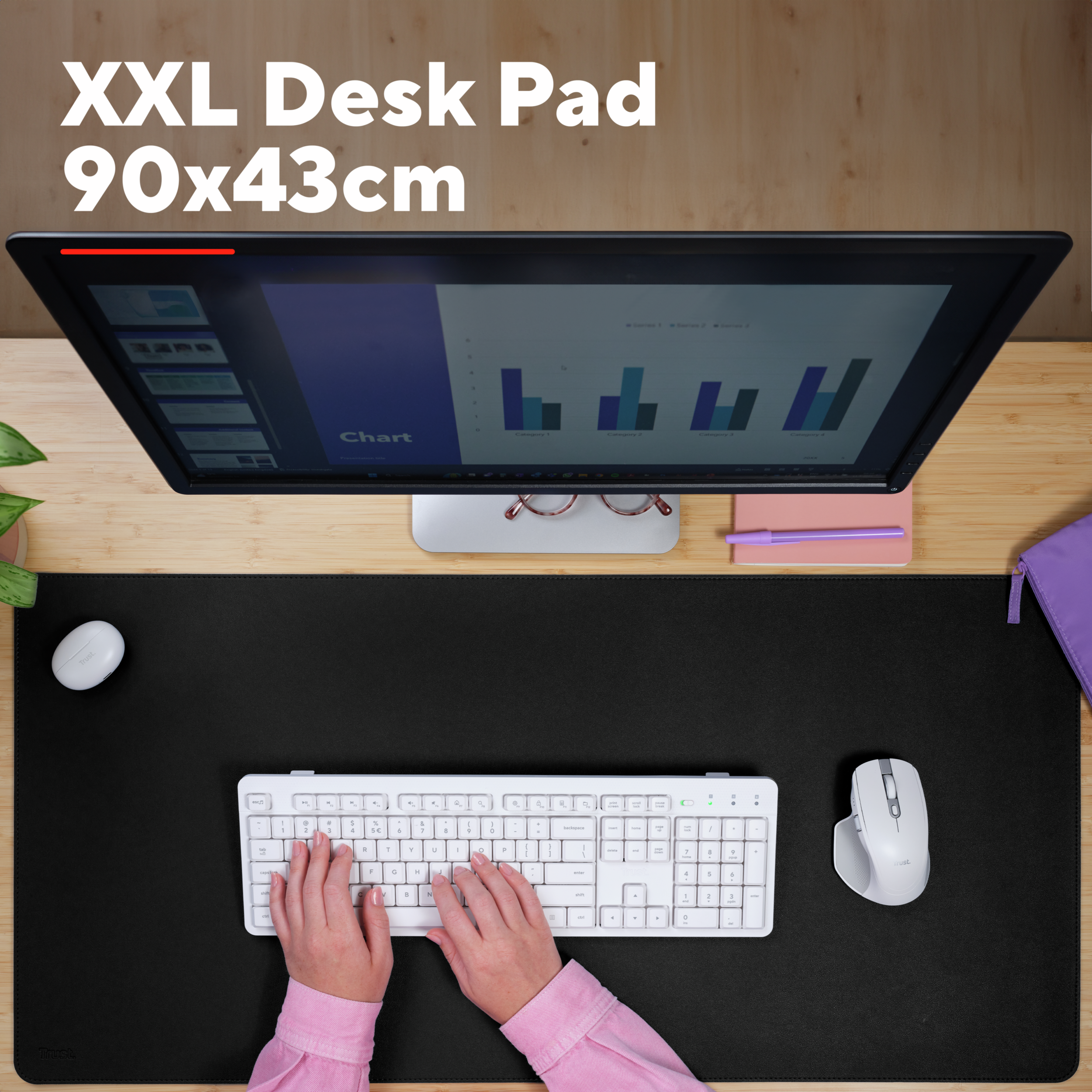An overhead shot of a desk with a black XXL desk pad, keyboard, mouse, monitor, and hands typing.