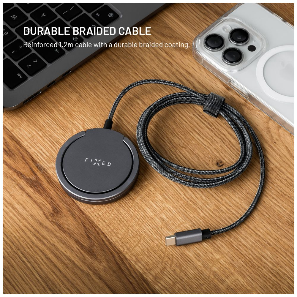 Ein geflochtenes Ladekabel, ein Ladegerät und ein Telefon liegen auf einer Holzoberfläche neben einer Laptop-Tastatur.