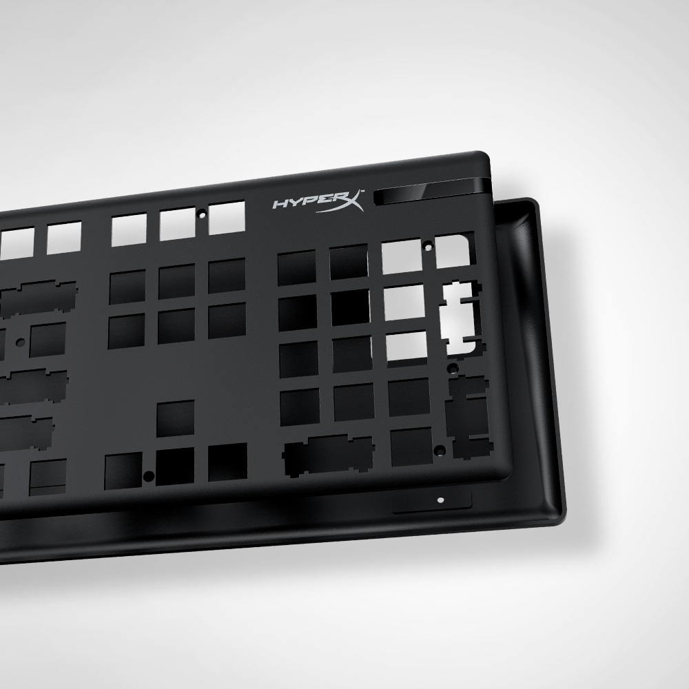 Czarna rama klawiatury z otworami na klawisze, widoczne logo HyperX. Tło jest białe.