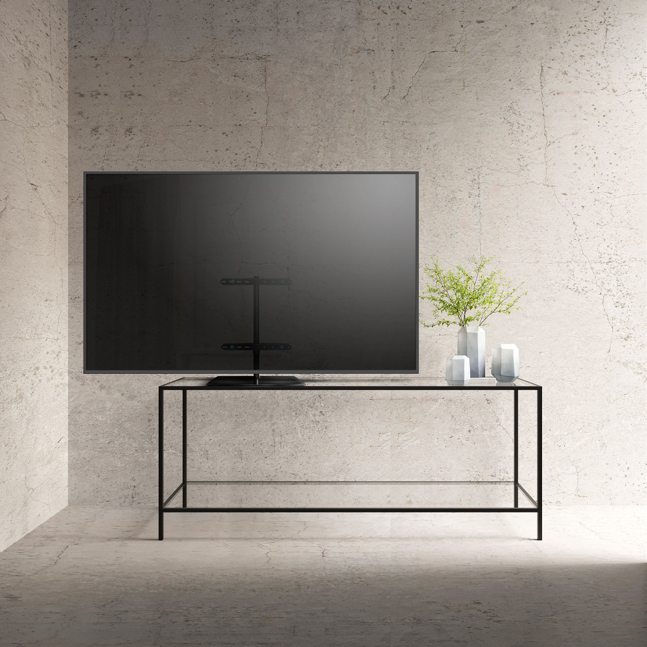 Un soggiorno moderno con una grande TV su un muro di cemento. Un tavolo di vetro ha vasi con verde.