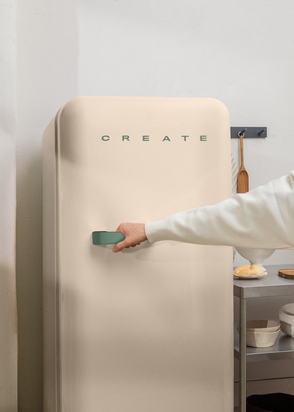 Una persona abre un frigorífico beige con un asa verde. La palabra 'CREATE' está en el frigorífico. Una escena de cocina.