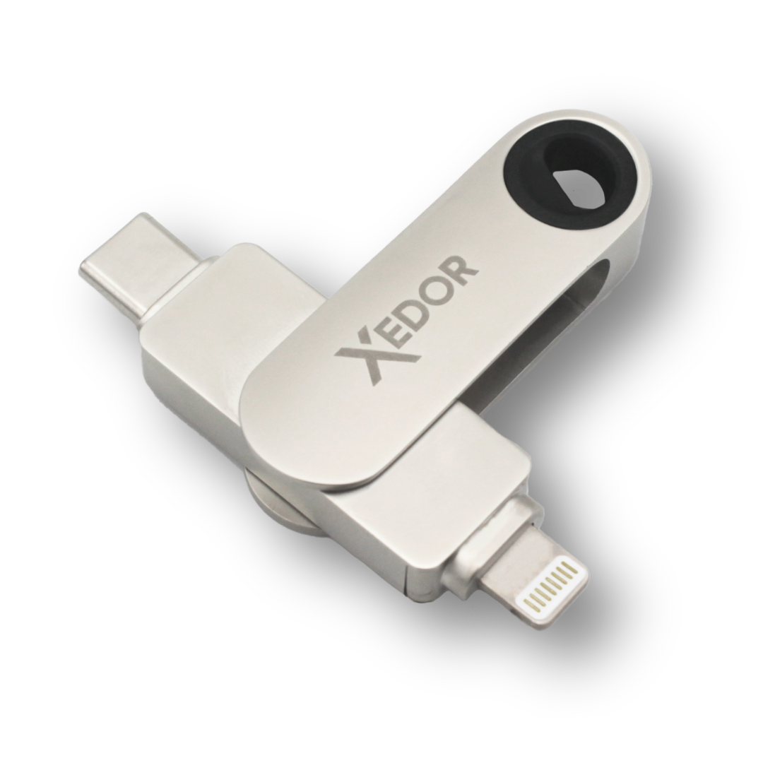 Srebrny pendrive Xedor z trzema złączami: USB-C, Lightning i obrotową sekcją, na czarnym tle.