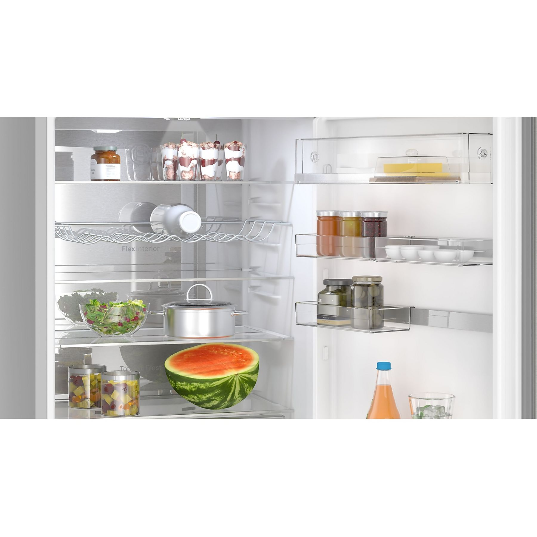 Interno del frigorifero pieno di cibo: anguria, insalata, vasetti, dessert e bevande. Scaffali e cassetti sono visibili.