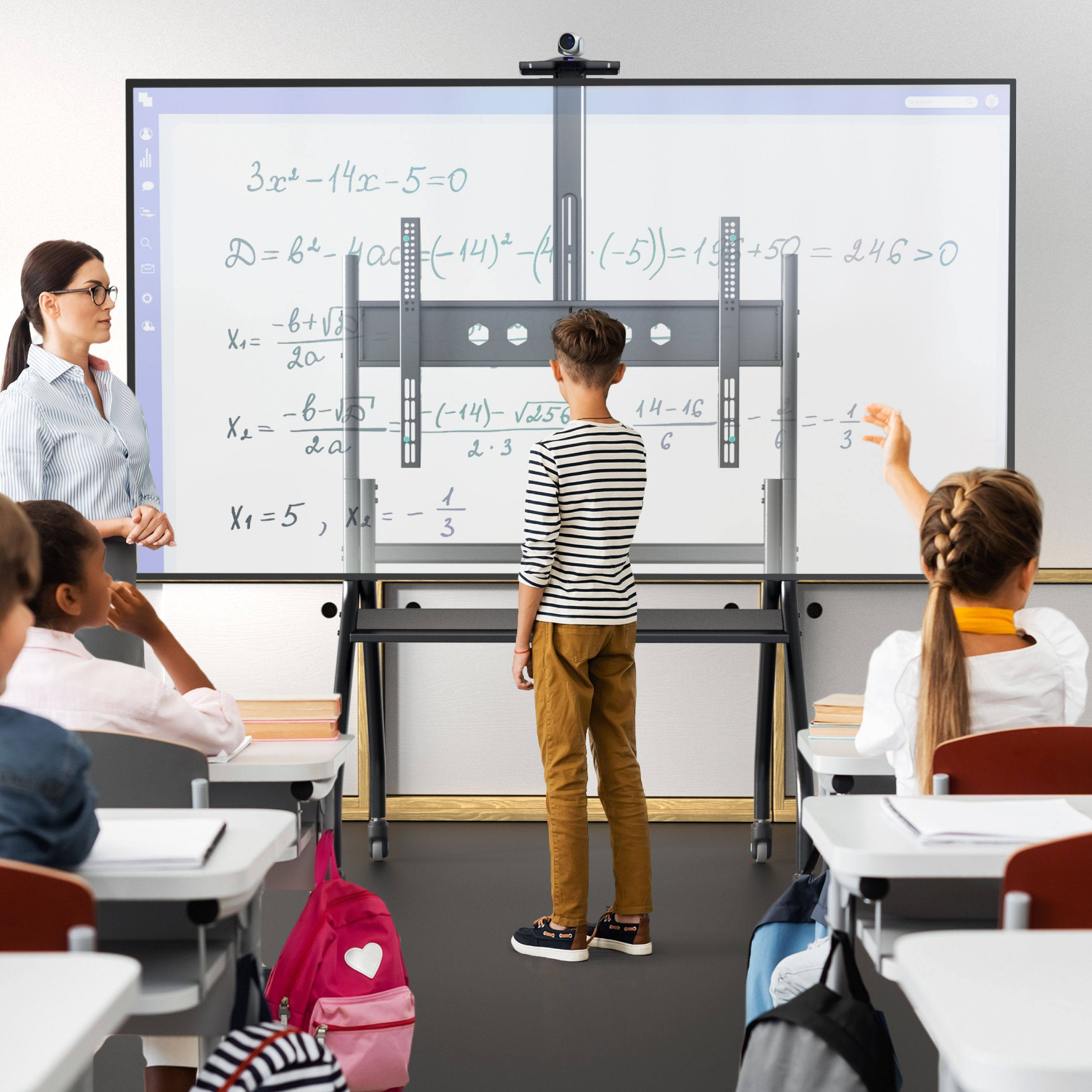 Scena w klasie. Chłopiec stoi przed tablicą z równaniami matematycznymi. Obecny jest nauczyciel i uczniowie.