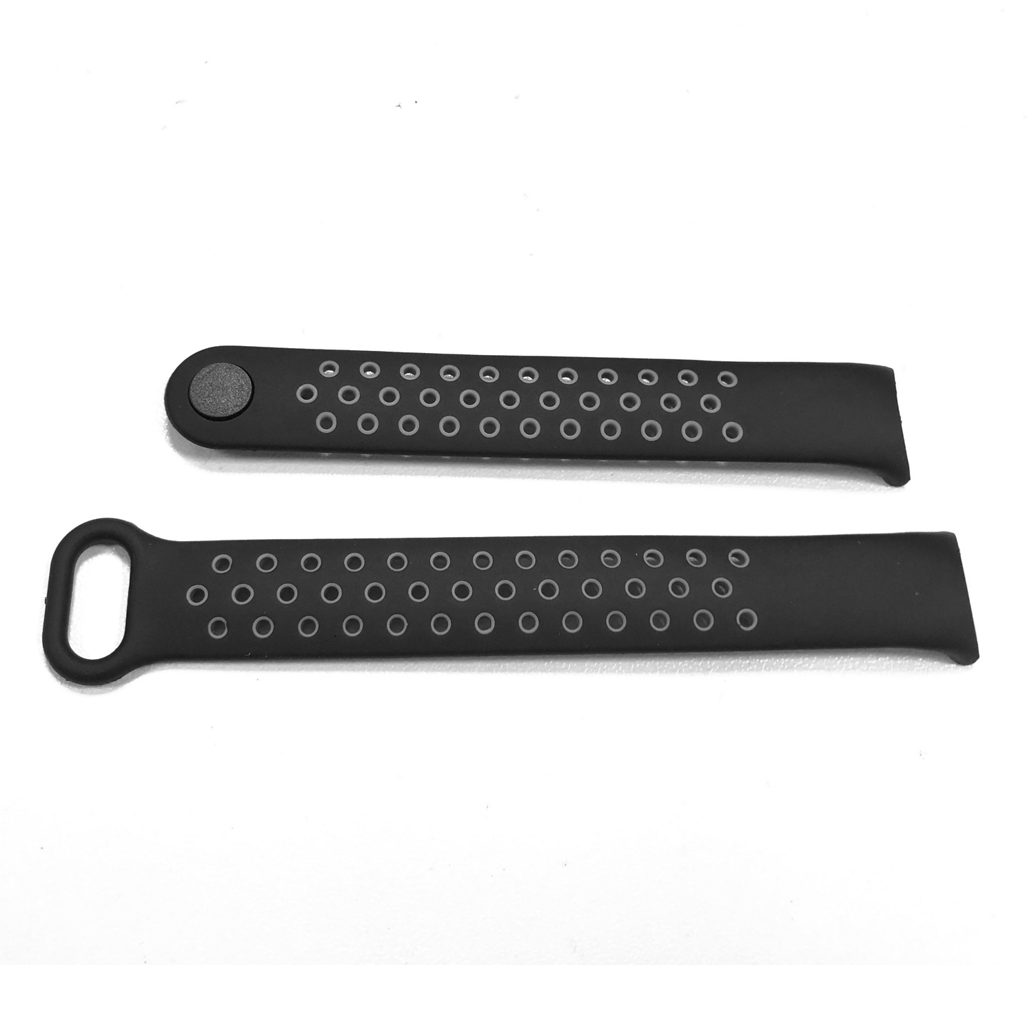 Zwei schwarze Armbänder mit kreisförmigen Perforationen liegen auf einer weißen Oberfläche. Ein Armband hat eine Schnalle, das andere einen Knopf.