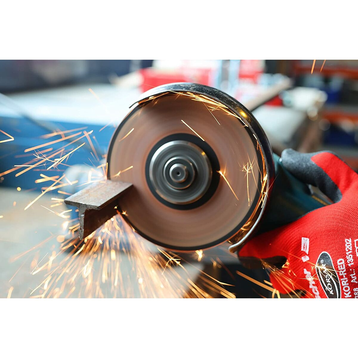 Una amoladora angular corta una viga de metal, saltan chispas. Una mano con guante rojo sostiene la amoladora.