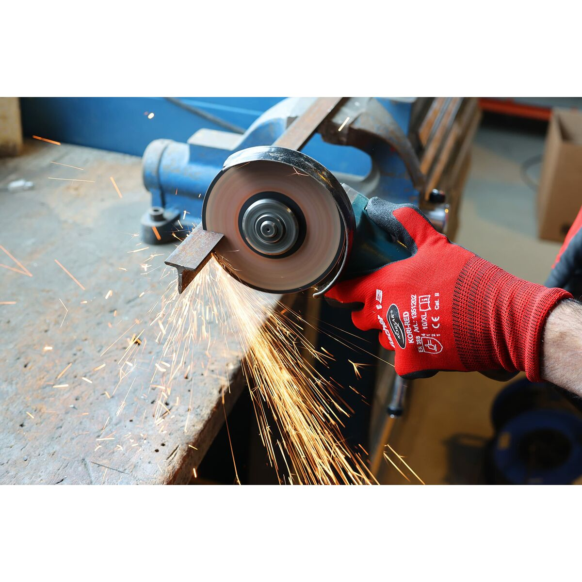Un trabajador usa una amoladora angular, cortando metal. Chispas vuelan. Guantes rojos en las manos del trabajador. Un tornillo de banco de metal en el fondo.