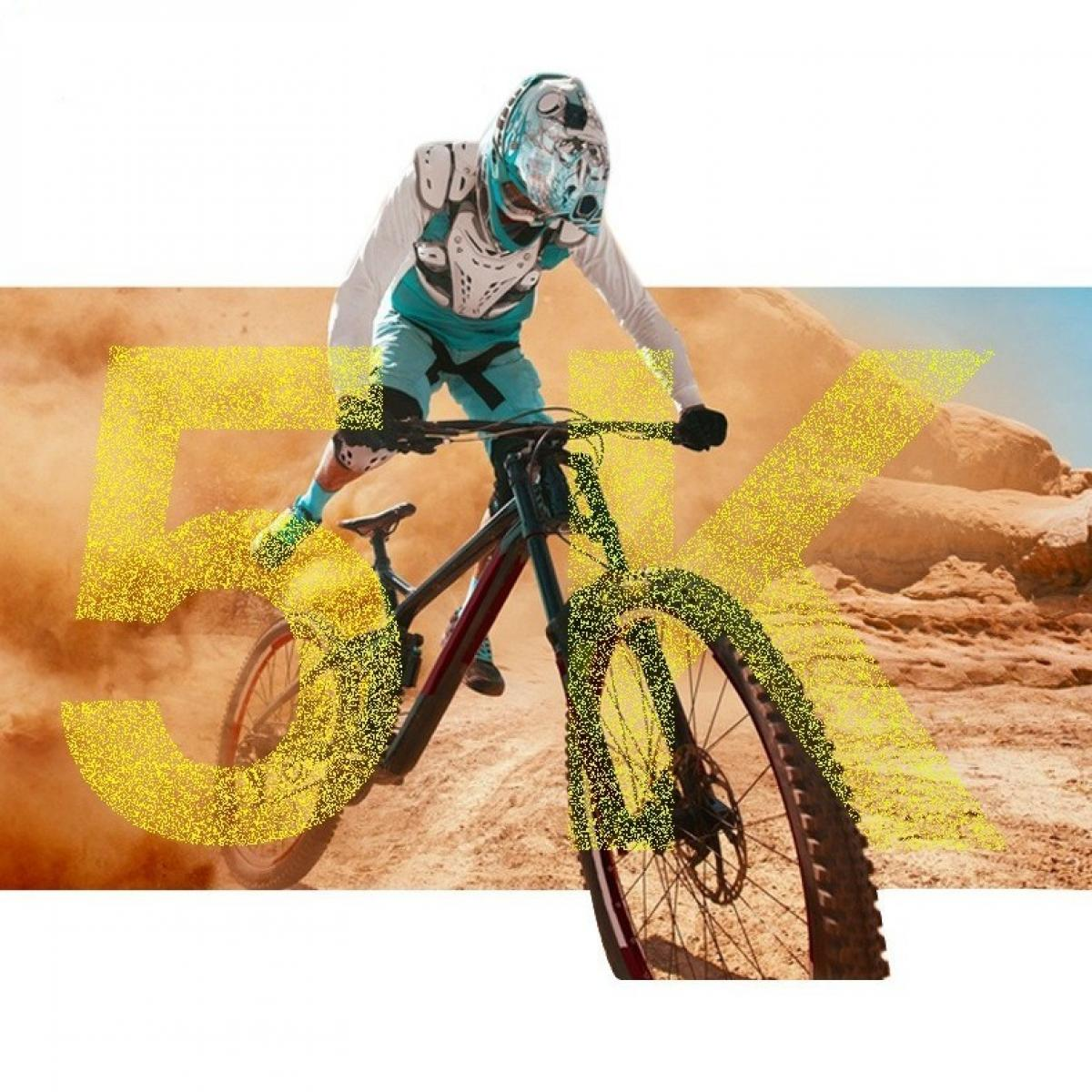 Ein Mountainbiker in Schutzkleidung fährt auf einem Feldweg, mit einem '5K'-Overlay. Staub steigt um das Fahrrad und den Fahrer auf.