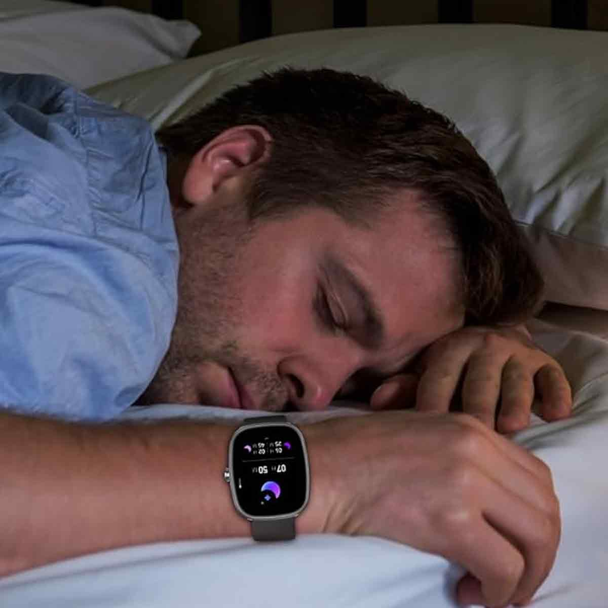 Ein Mann schläft im Bett und trägt eine Smartwatch, die die Zeit anzeigt. Die Szene umfasst ein Kissen und ein blaues Hemd.