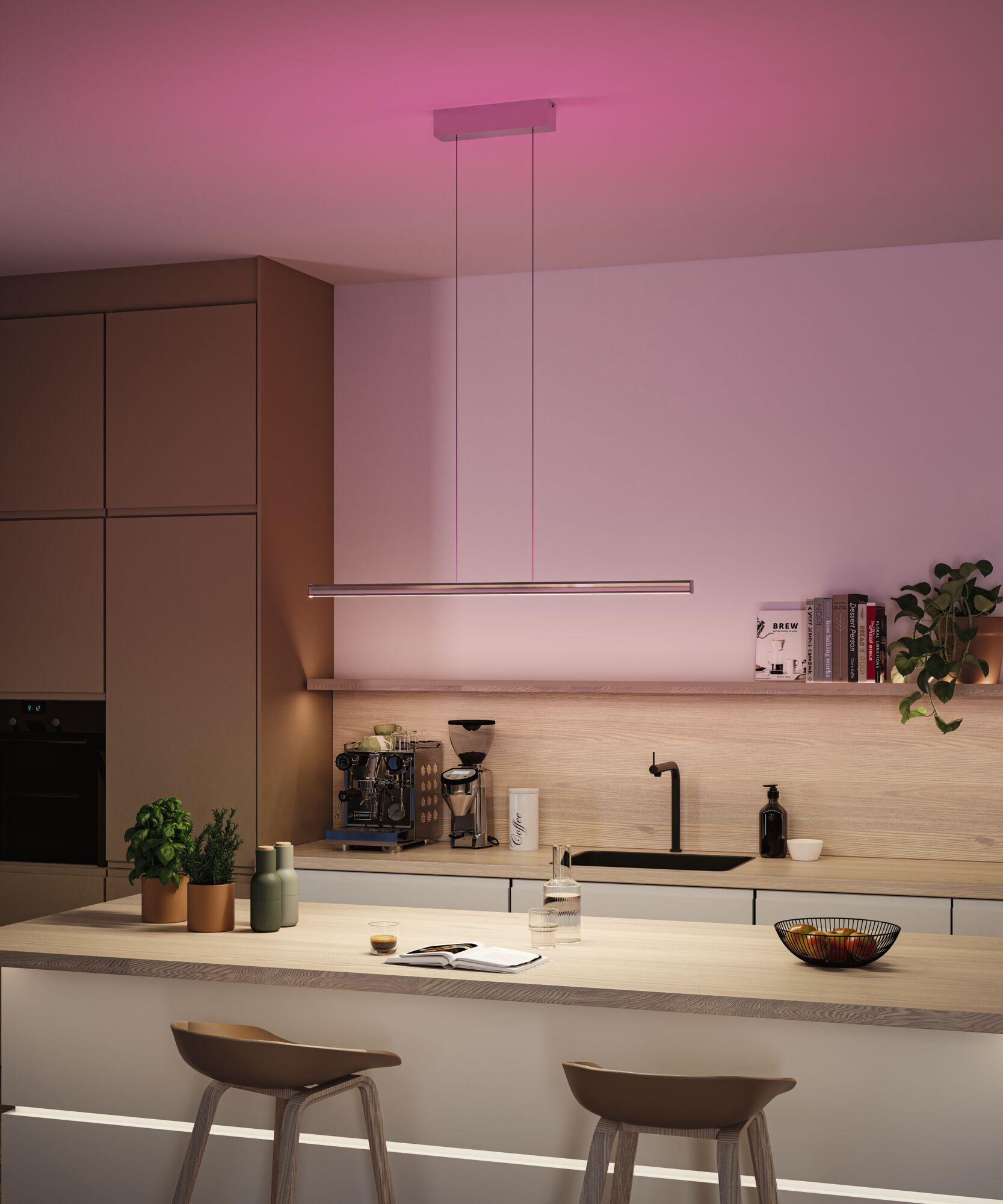 Moderne Küche mit Insel, Pendelleuchte und Barhockern. Kaffeemaschine, Bücher und Pflanzen ergänzen das moderne Design.