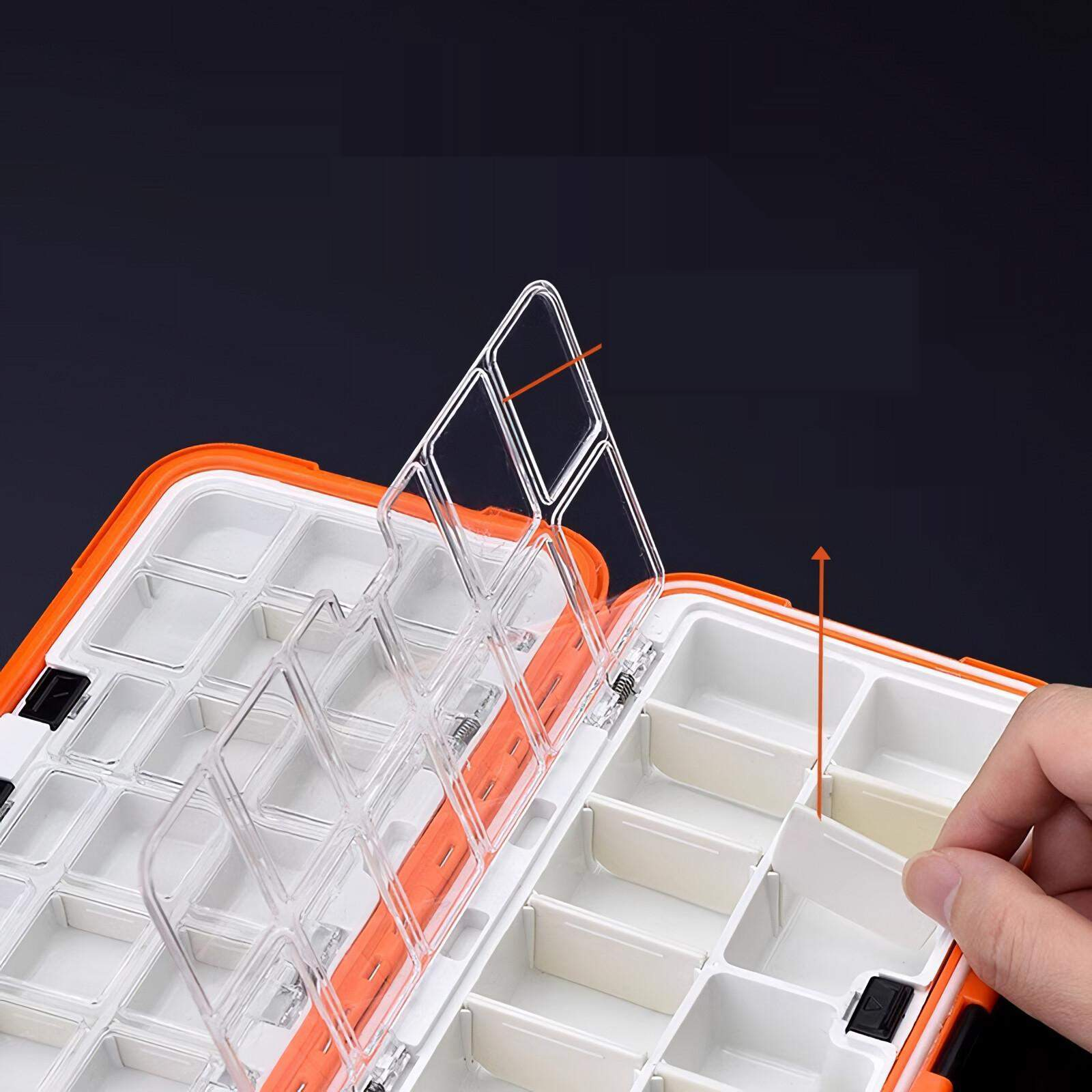 Eine orange-weiße Tackle-Box ist geöffnet, eine Hand hebt eine Trennwand an. Der Deckel ist transparent.