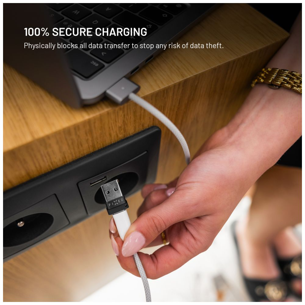 Eine Person steckt ein USB-Kabel in einen Anschluss. Das Kabel ist mit einem Laptop verbunden. Die Szene spielt auf einem Holztisch.