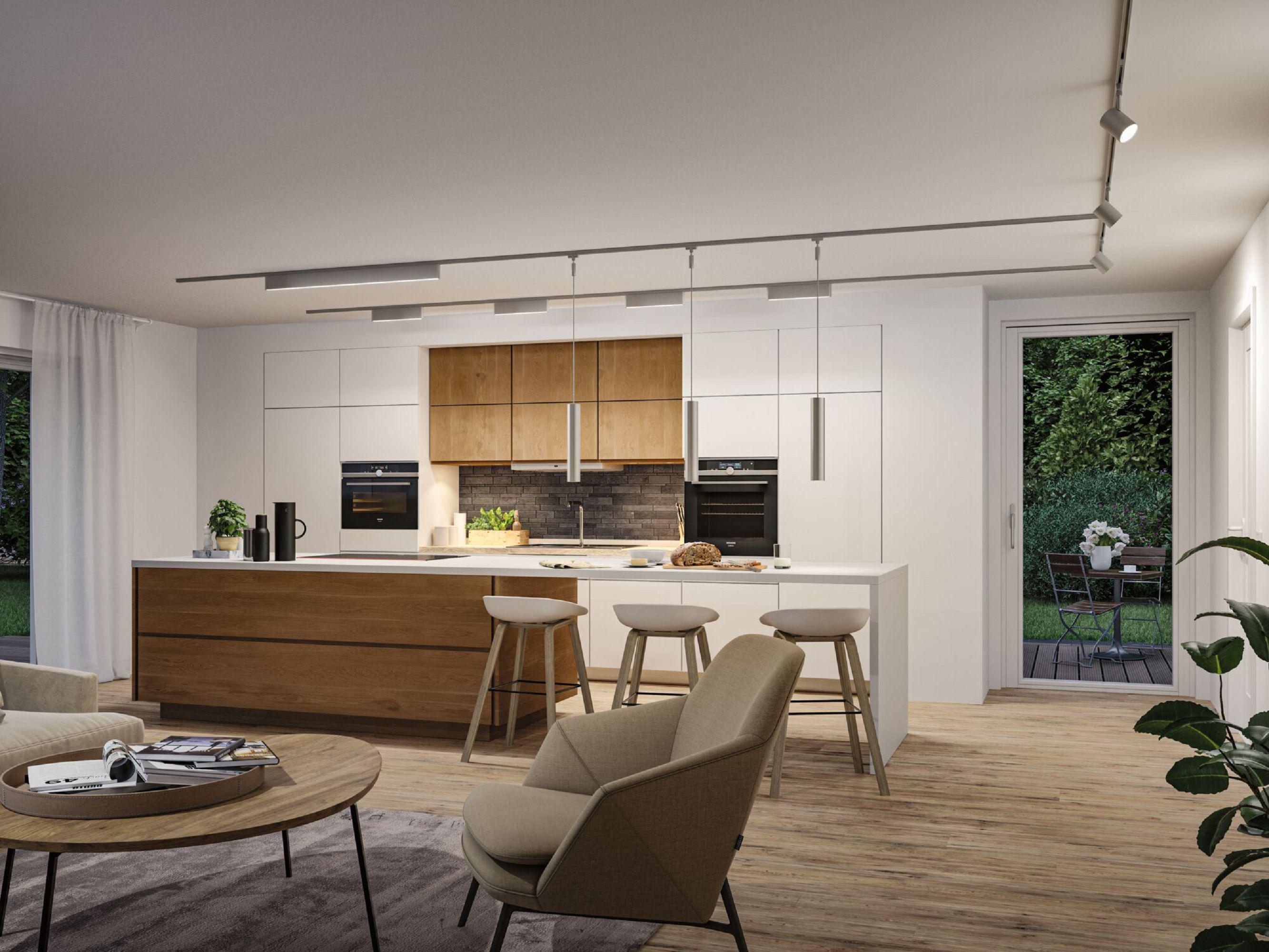 Nowoczesna kuchnia z wyspą i stołkami. Jadalnia w tle. Widok na zewnątrz przez szklane drzwi.