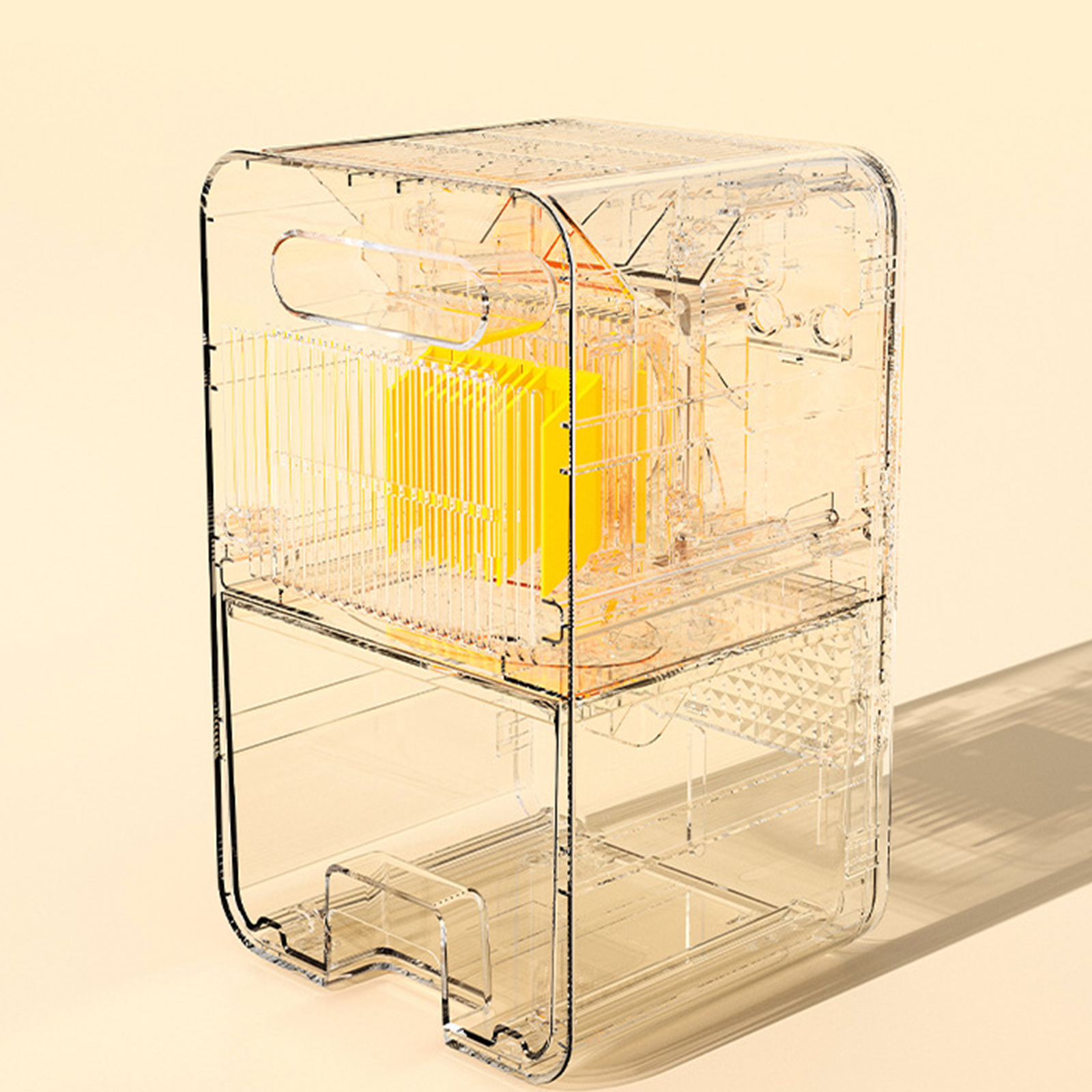 Eine transparente Plastikbox mit gelben Innenteilen. Die Box hat einen Griff und steht vor einem beigefarbenen Hintergrund.