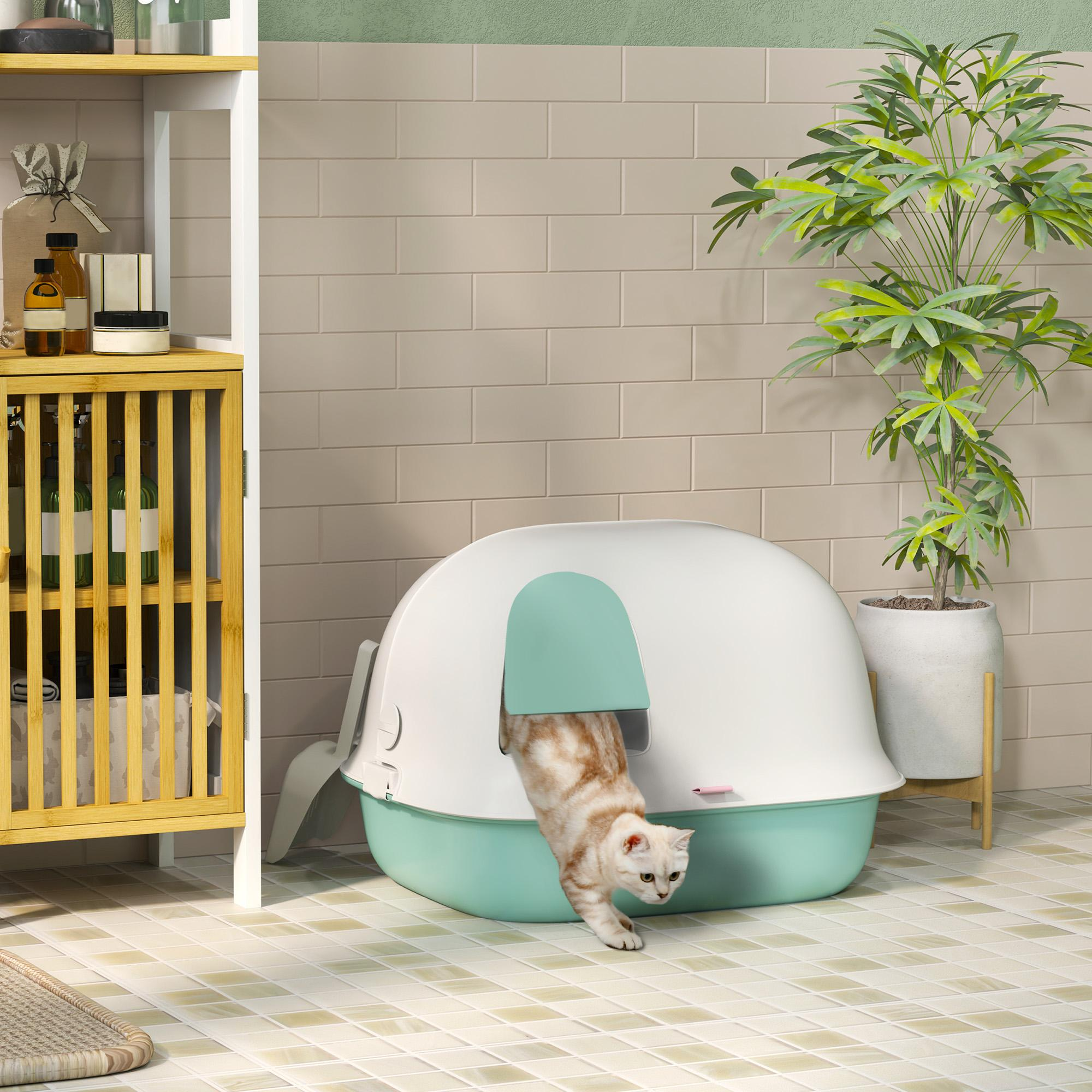 Eine Katze verlässt eine überdachte Katzentoilette. Ein Regal und eine Topfpflanze sind im Hintergrund.