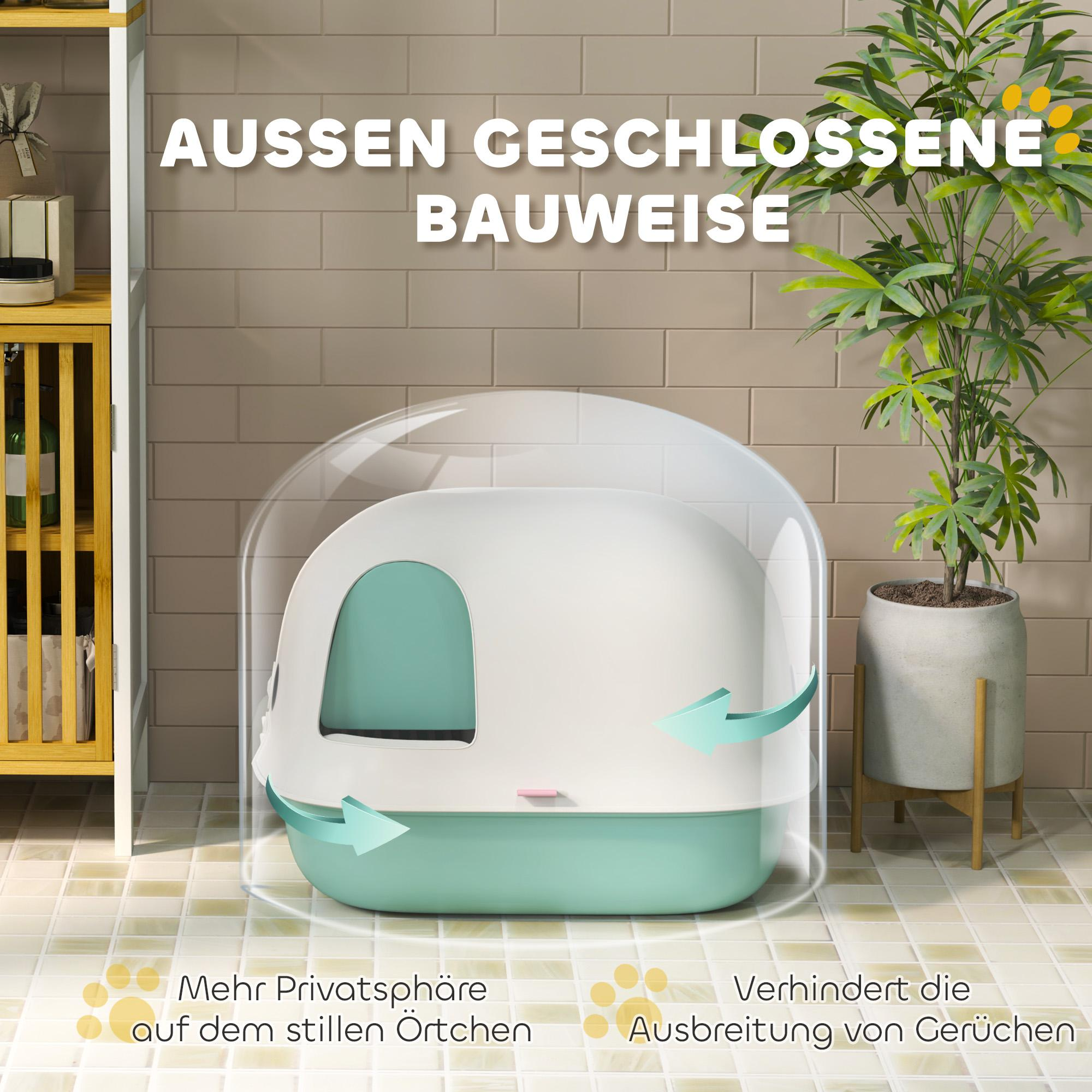 Eine weiße und türkisfarbene Katzentoilette mit einer transparenten Kuppel, in einem Badezimmer mit Pflanze und Schrank.