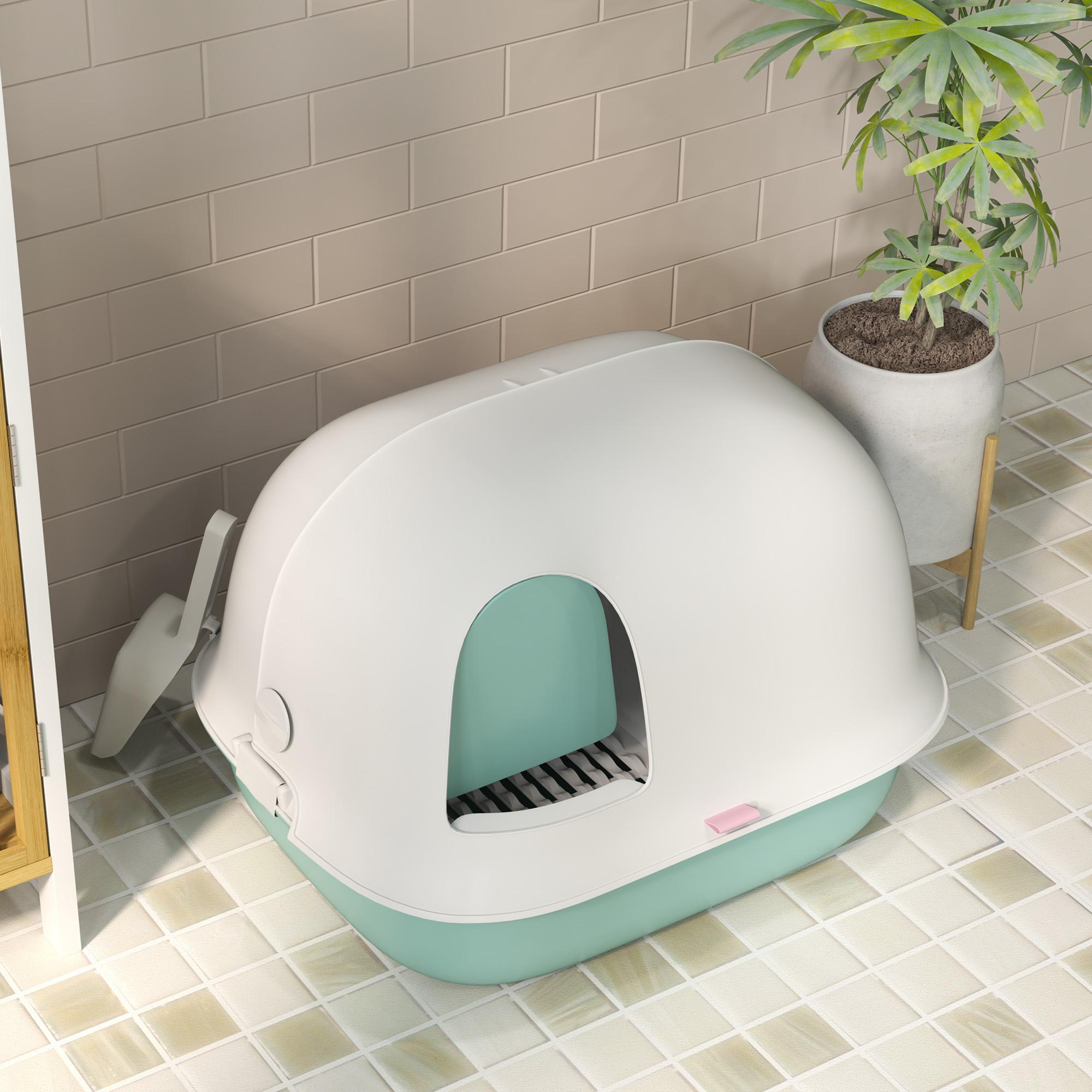 Eine Katzentoilette, weißes Oberteil und türkisfarbene Basis, steht auf einem gefliesten Boden. Im Hintergrund steht eine Pflanze in einem Topf.