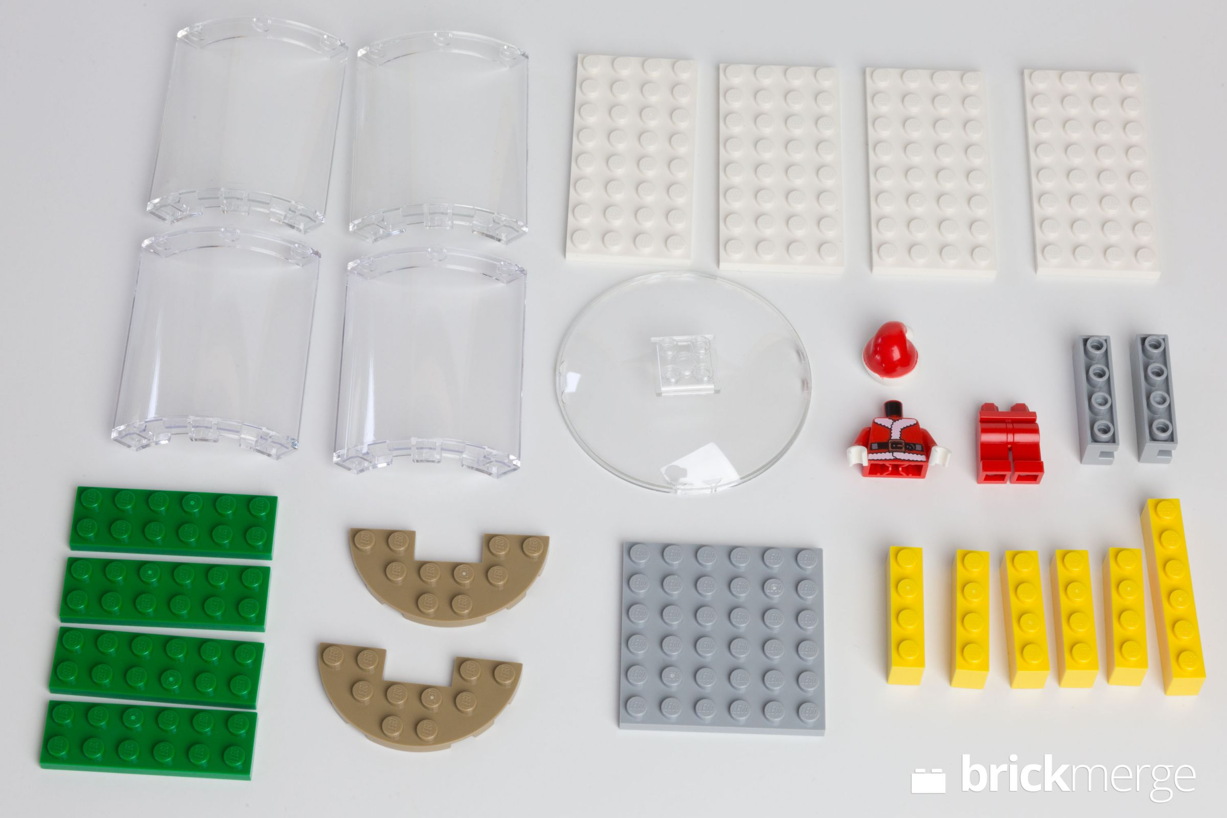 Verschiedene LEGO-Teile sind auf einer weißen Oberfläche angeordnet, darunter transparente, weiße, grüne, gelbe und graue Blöcke.