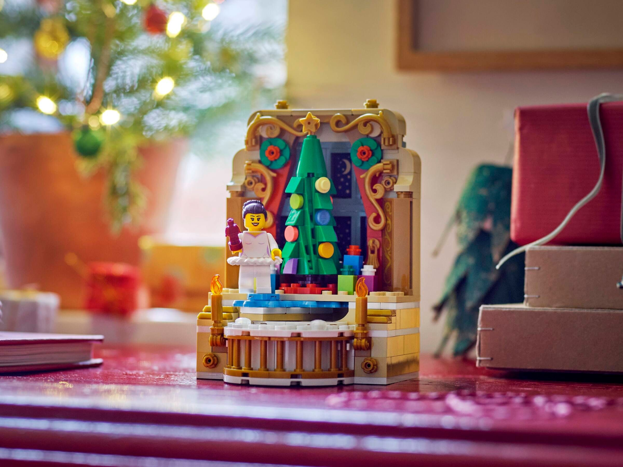 Eine Lego-Weihnachtsszene mit Baum, Engel und Geschenken. Die Szene spielt auf einer roten Oberfläche und hat einen unscharfen Hintergrund.