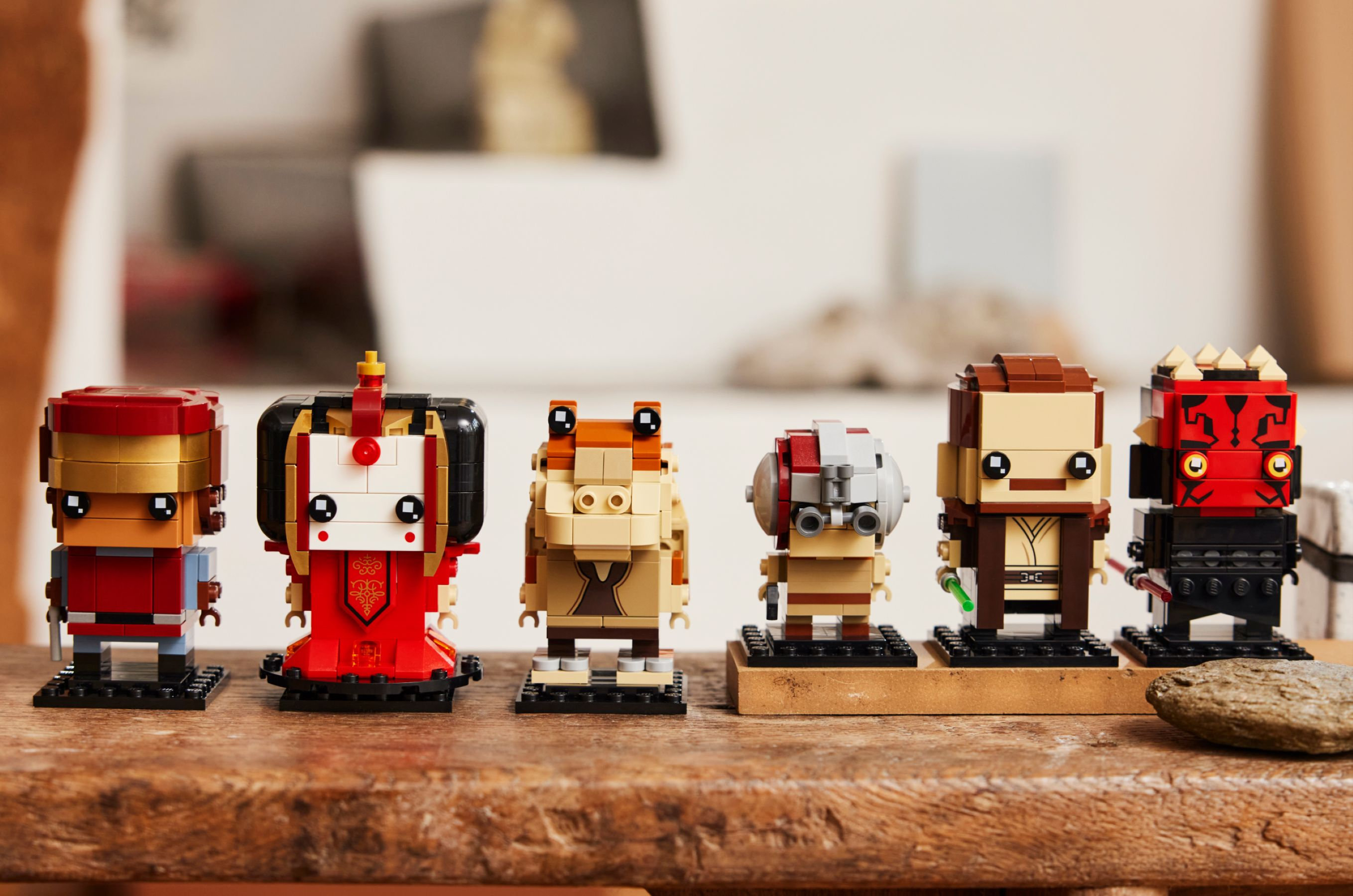LEGO Star Wars-Figuren werden auf einer Holzoberfläche ausgestellt. Die Figuren umfassen Iron Man, Padmé Amidala, Jar Jar Binks und andere.