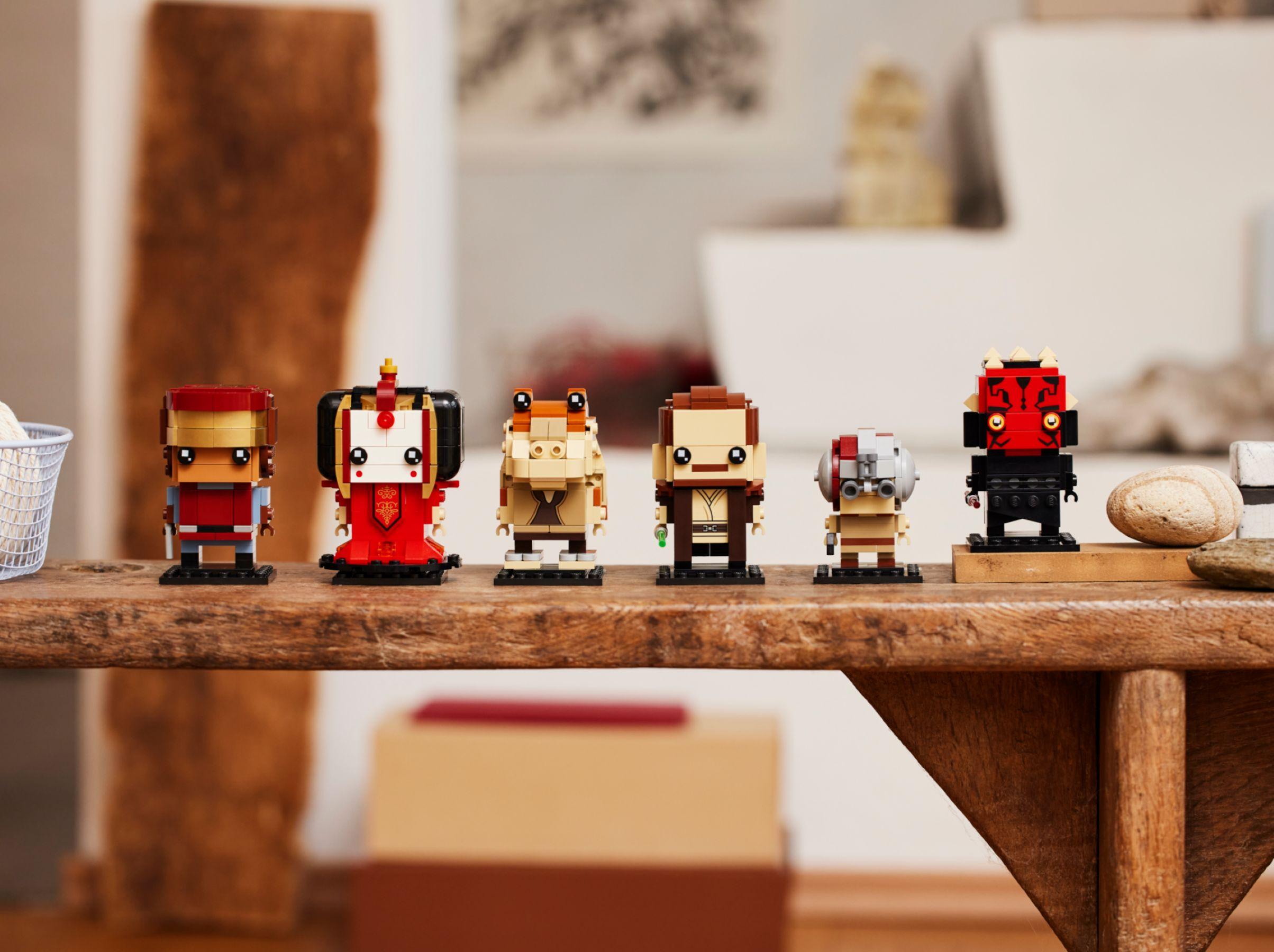 Sechs Lego-Figuren von Star Wars-Charakteren stehen auf einem Holzregal. Dazu gehören Darth Maul, Obi-Wan und andere.