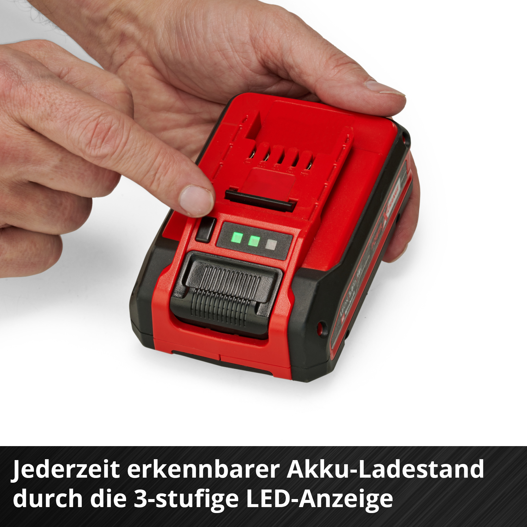 Un dito tocca una batteria rossa. La batteria ha un display a LED con tre luci verdi.