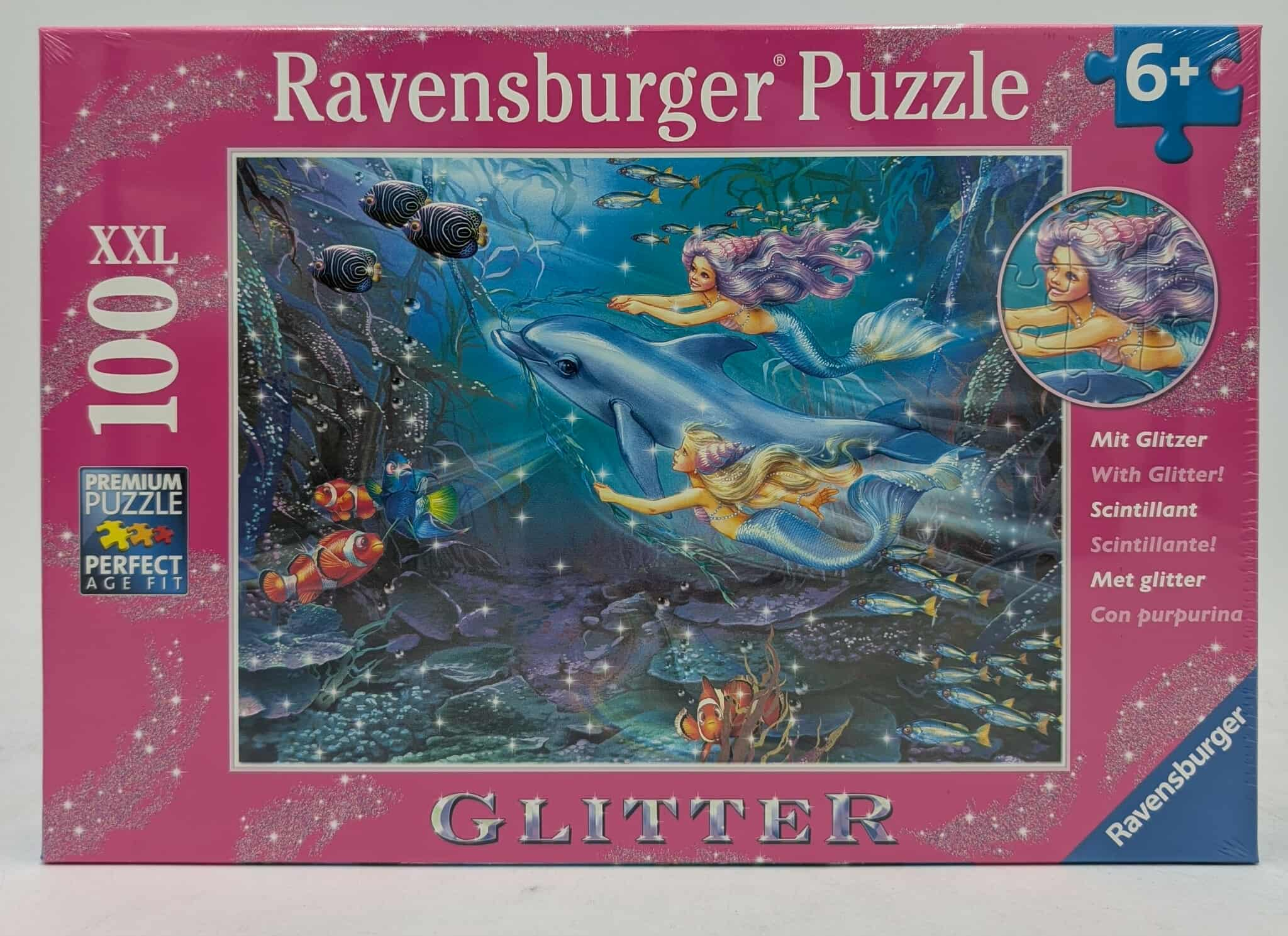 Eine Puzzledose zeigt Meerjungfrauen, die mit einem Delfin schwimmen, umgeben von Fischen, in einer glitzernden Unterwasserszene, mit einem Puzzleteil.