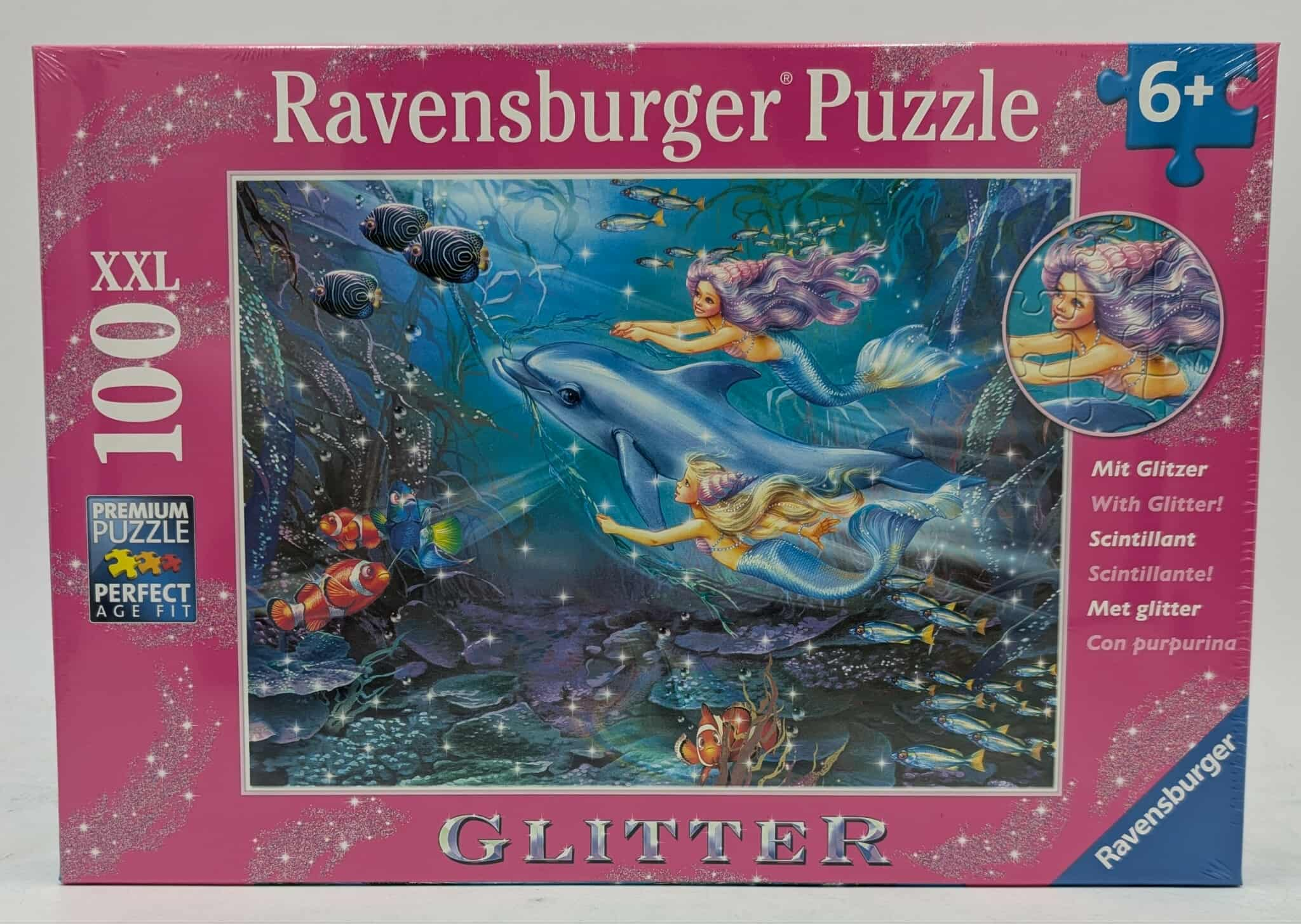 Puzzledose mit Meerjungfrauen, Delfin und Fischen in einer Unterwasserszene. Die Box ist rosa und sagt 'Ravensburger Puzzle.'