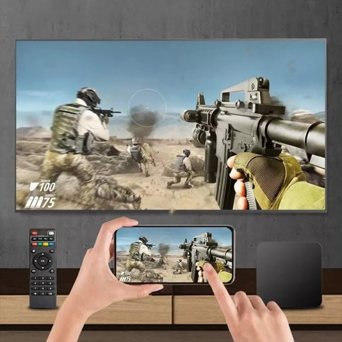 Eine Person hält ein Telefon, das eine Videospielszenen mit Soldaten und Waffen zeigt. Ein Fernseher zeigt dieselbe Szene. Eine Fernbedienung und eine schwarze Box liegen auf einem Tisch.