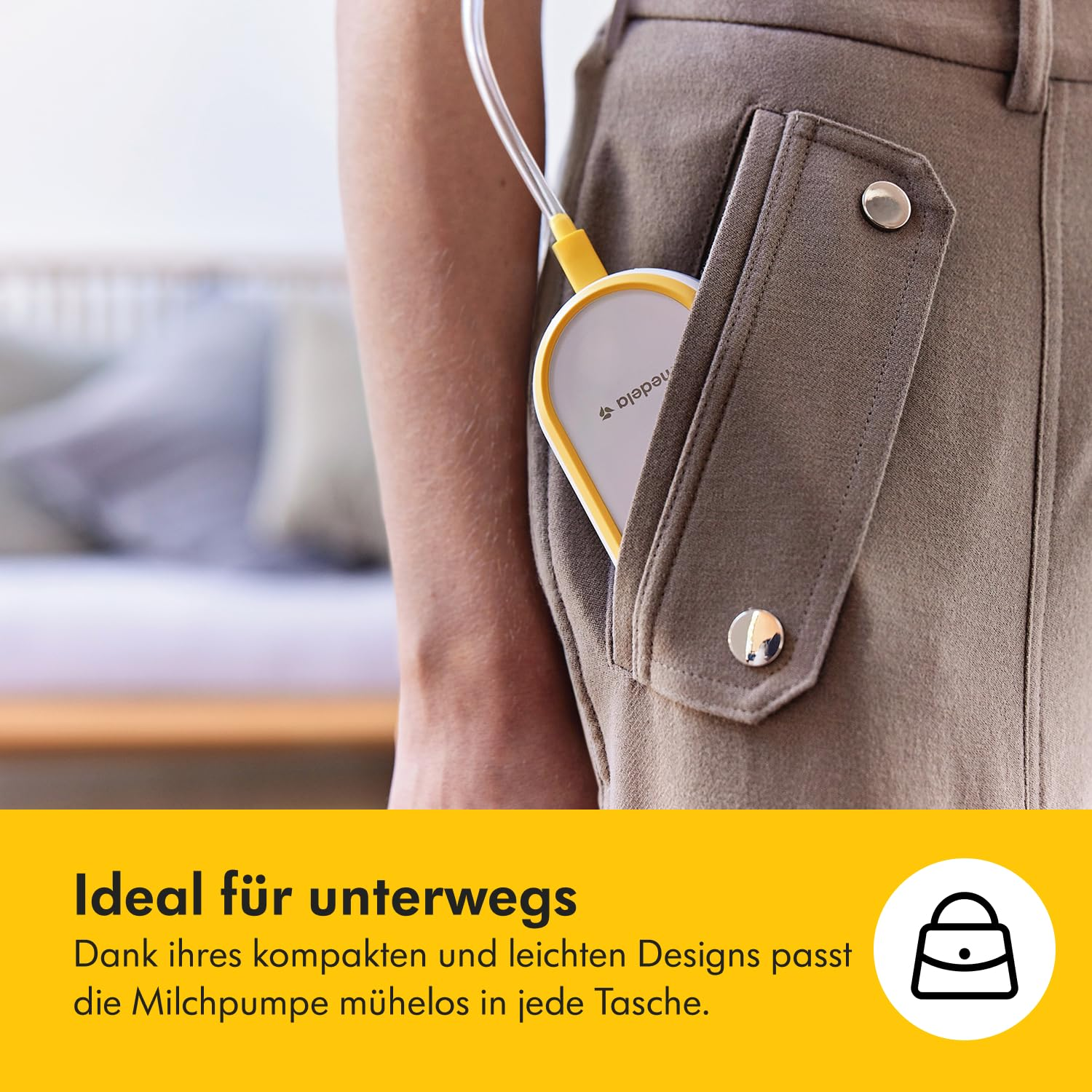 Eine Brustpumpe in einer Tasche. Eine Person hält eine Brustpumpe mit gelbem Rand. Die Brustpumpe befindet sich in einer Tasche einer braunen Hose.