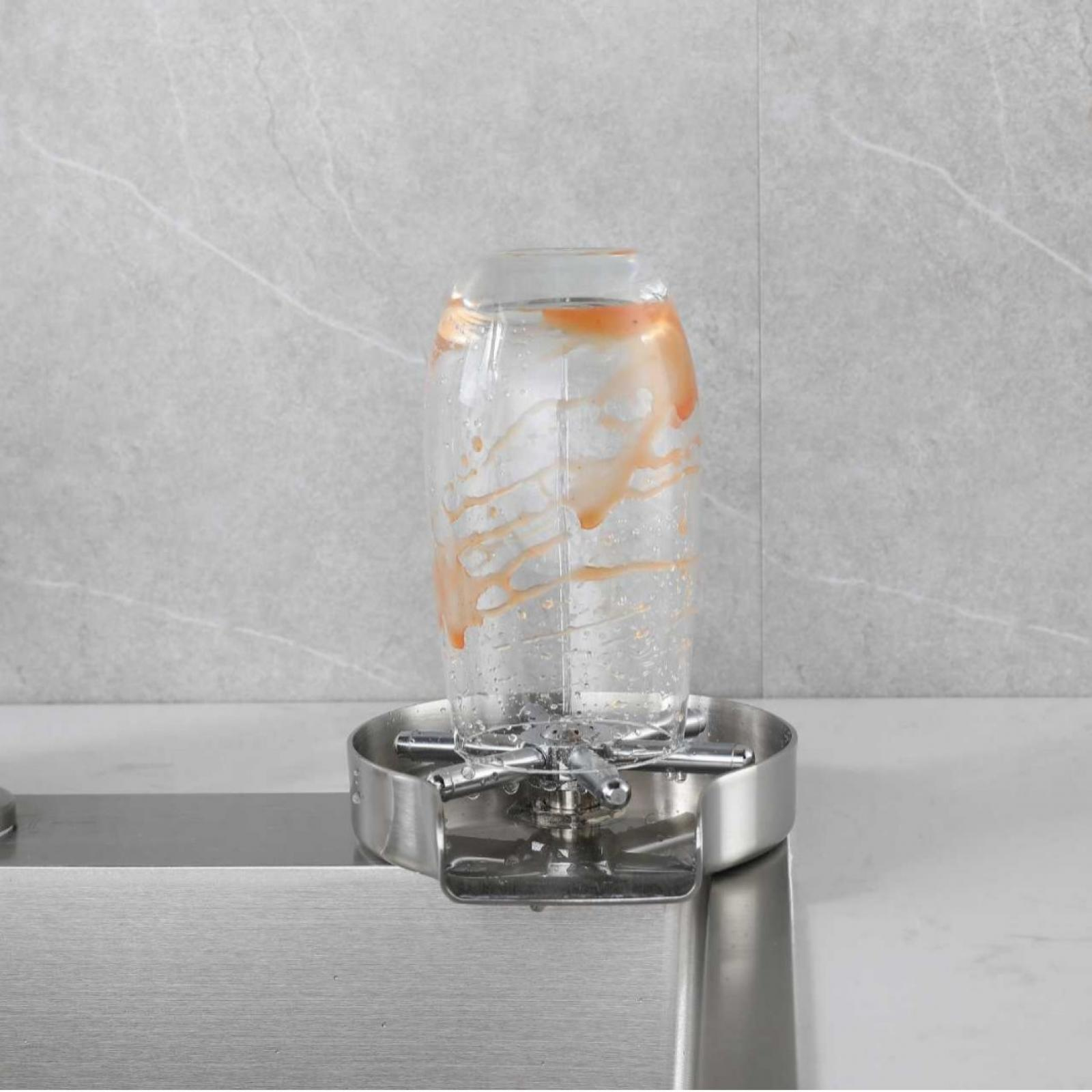 Ein Glas mit orangefarbenen Flecken steht in einem Edelstahlspüler. Der Hintergrund ist eine graue Fliesenwand.