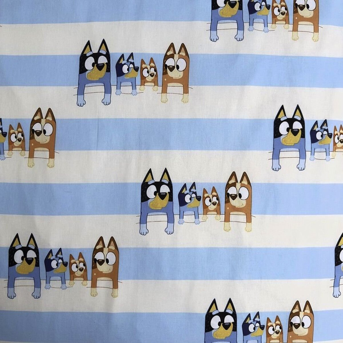 Gemusterter Stoff mit blau-weißen Streifen. Cartoon-Hunde wiederholen sich über den Stoff.