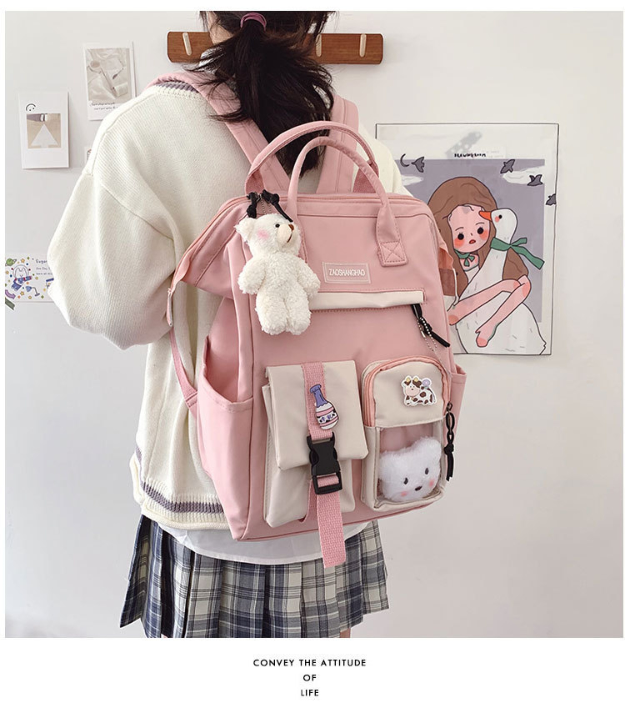 Eine Person mit weißem Pullover und kariertem Rock von hinten, trägt einen pinkfarbenen Rucksack mit mehreren Taschen und einem Teddybär.