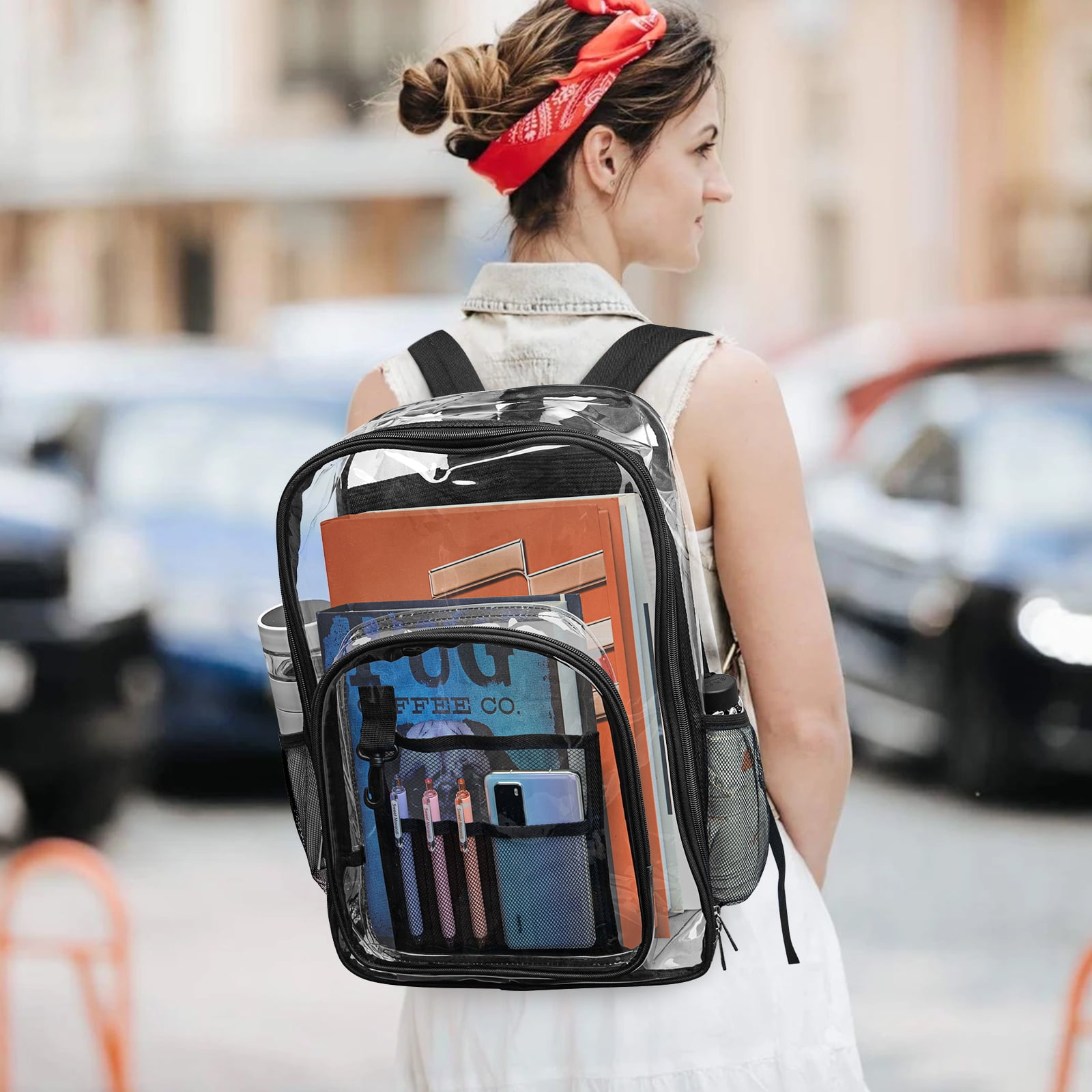 Frau mit transparentem Rucksack, gefüllt mit Büchern und Stiften, rotes Stirnband. Autos und Gebäude im Hintergrund.