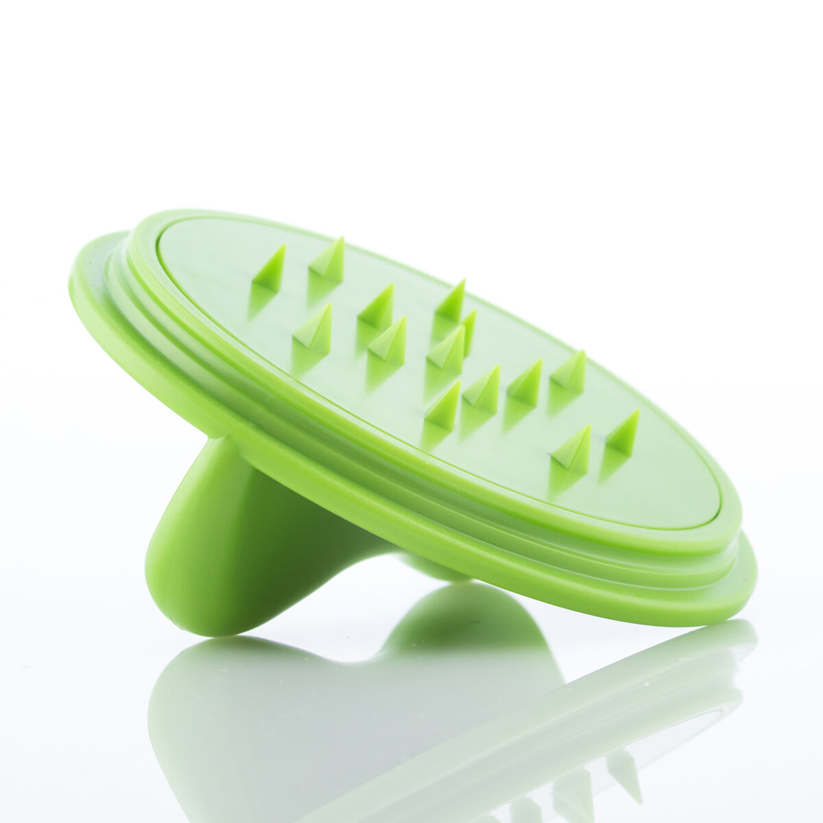 Un massaggiatore per cuoio capelluto verde con punte triangolari. Ha un manico arrotondato e poggia su una superficie bianca riflettente.