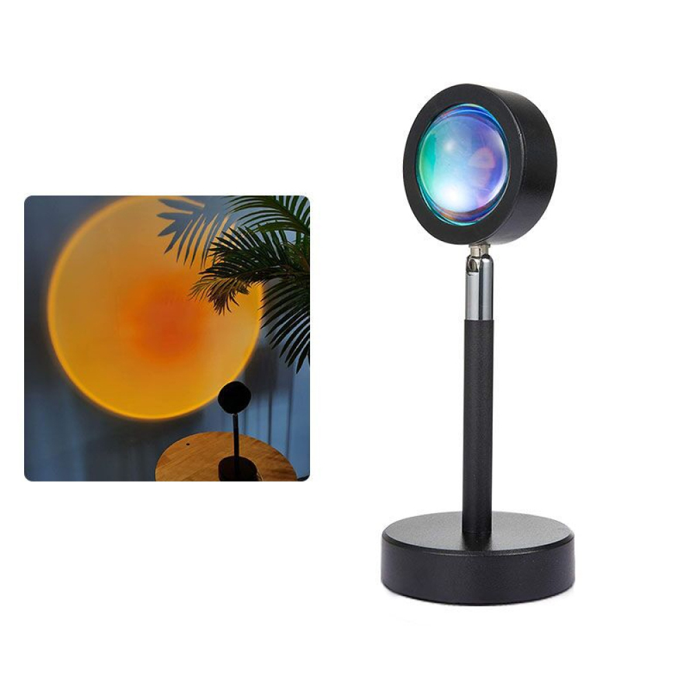Eine Lampe, die ein farbenfrohes Licht projiziert. Der Einsatz zeigt den projizierten Sonnenuntergang, Palmenblätter und eine kleine Lampe auf einem Tisch.