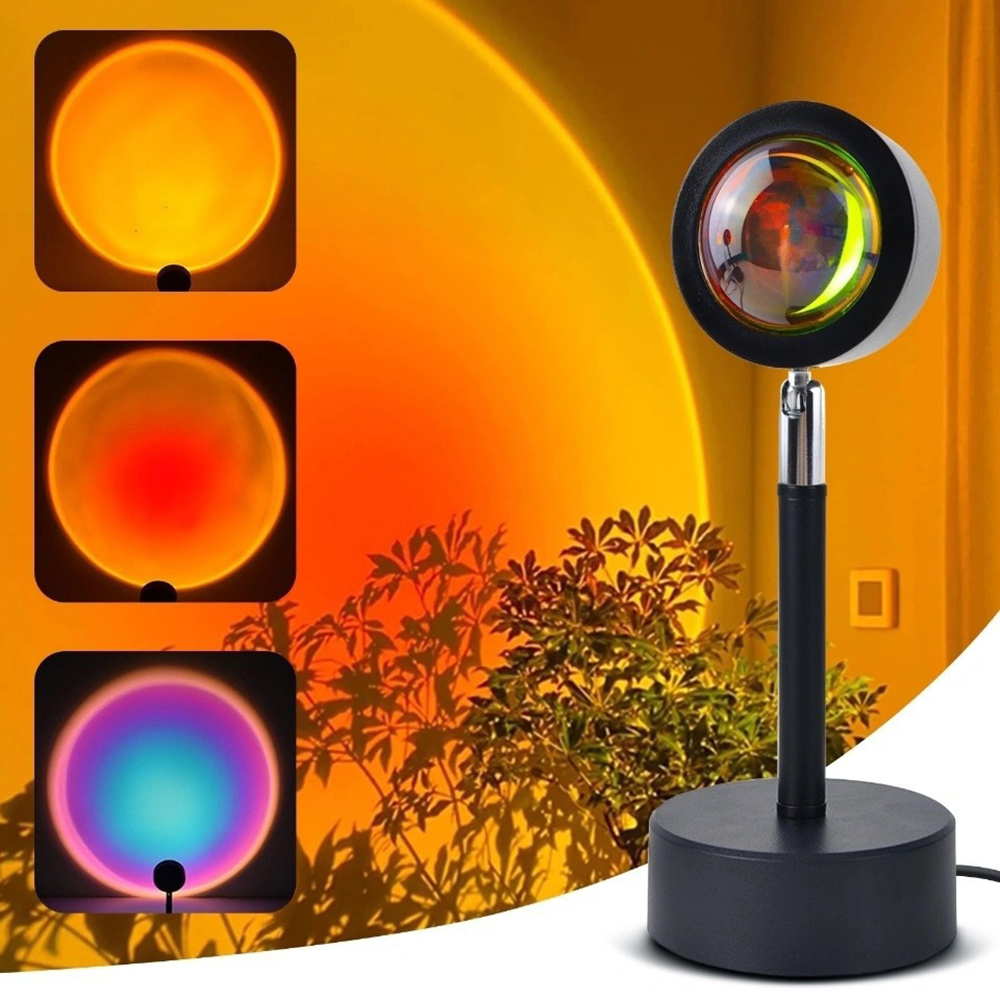Eine Sonnenuntergangslampe zeigt drei Lichtfarben: Orange, Rot und Blau. Die Lampe ist schwarz und hat einen runden Kopf. Im Hintergrund befindet sich eine Pflanze.