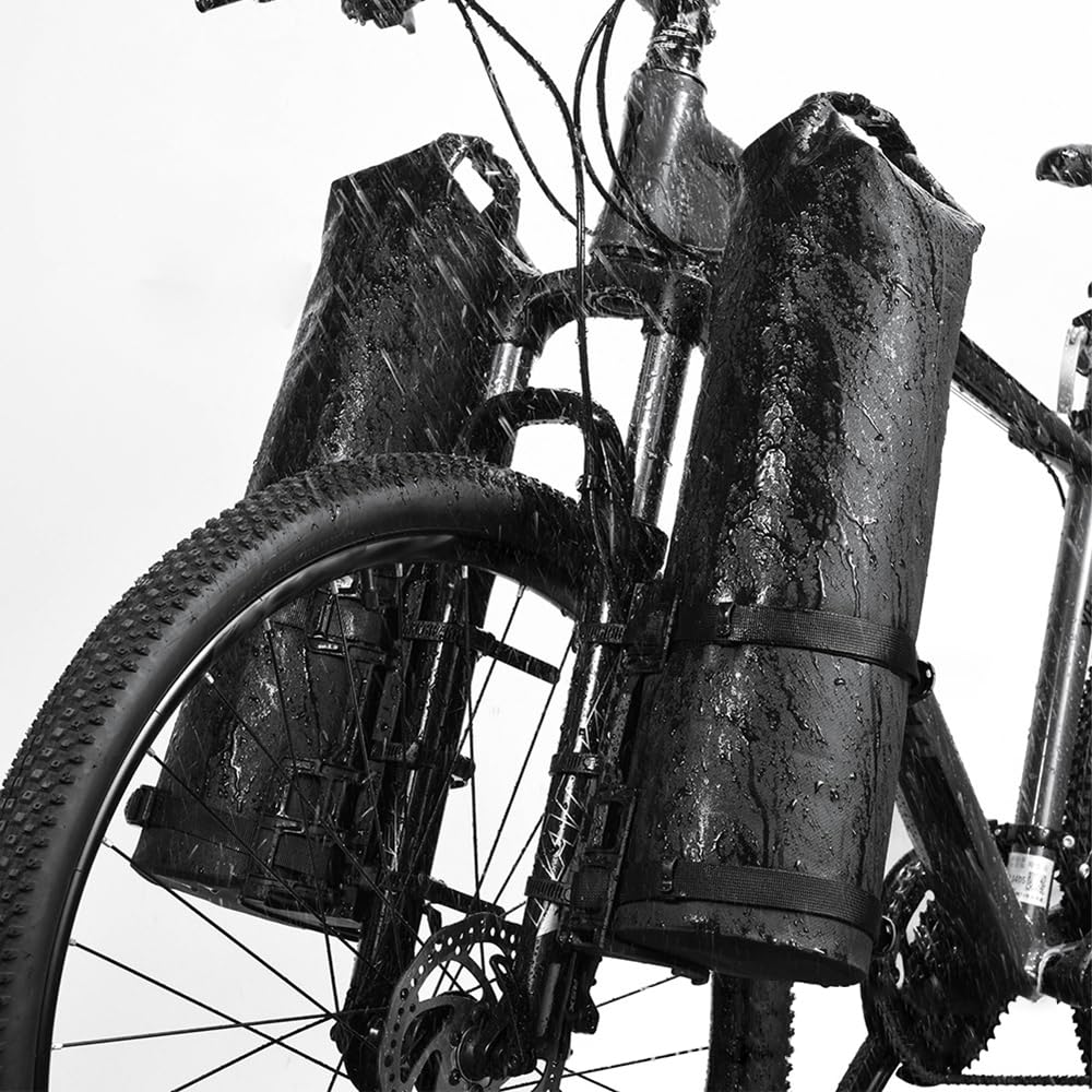 Schwarzes Fahrrad mit Packtaschen, nass vom Regen. Vorderrad, Rahmen und Lenker sichtbar. Taschen vorne am Fahrrad befestigt.