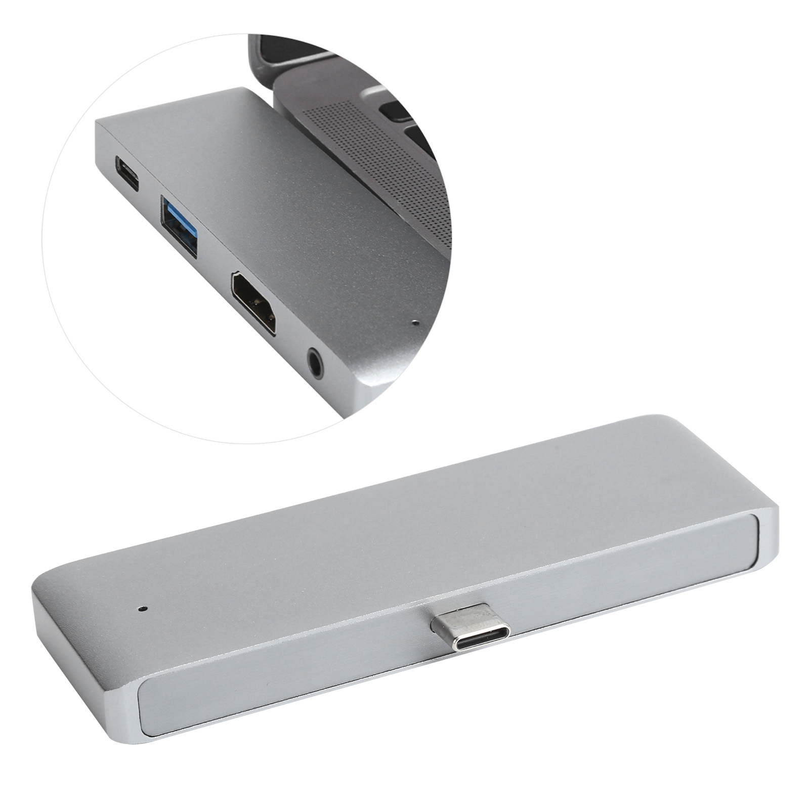 Ein silberner USB-C-Hub mit mehreren Anschlüssen, darunter USB, HDMI und Audio. Im Hintergrund ist ein Laptop.