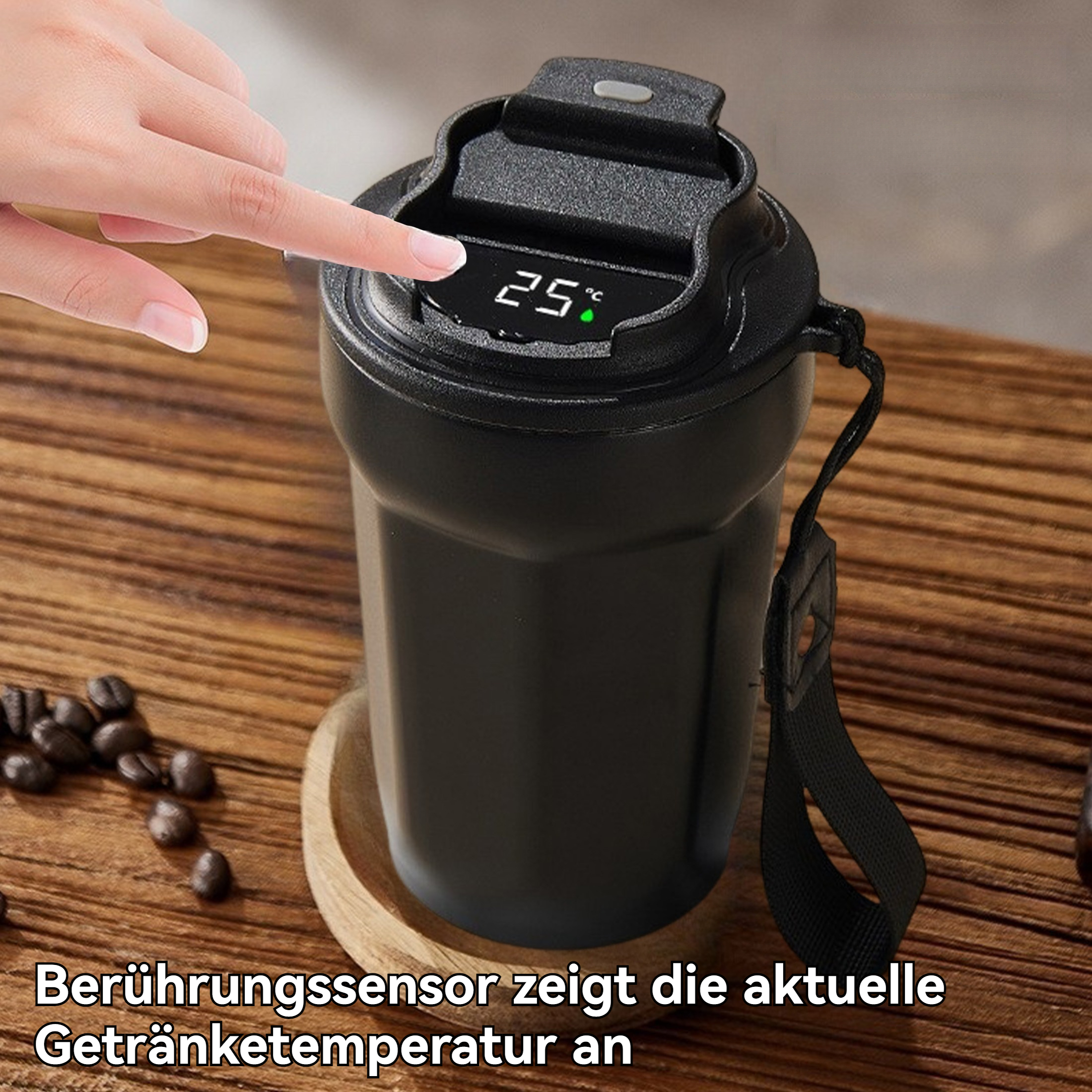 Eine Hand berührt einen schwarzen Reisebecher. Der Becher zeigt 25°C an. Kaffeebohnen und ein Holzlöffel liegen auf Holz.
