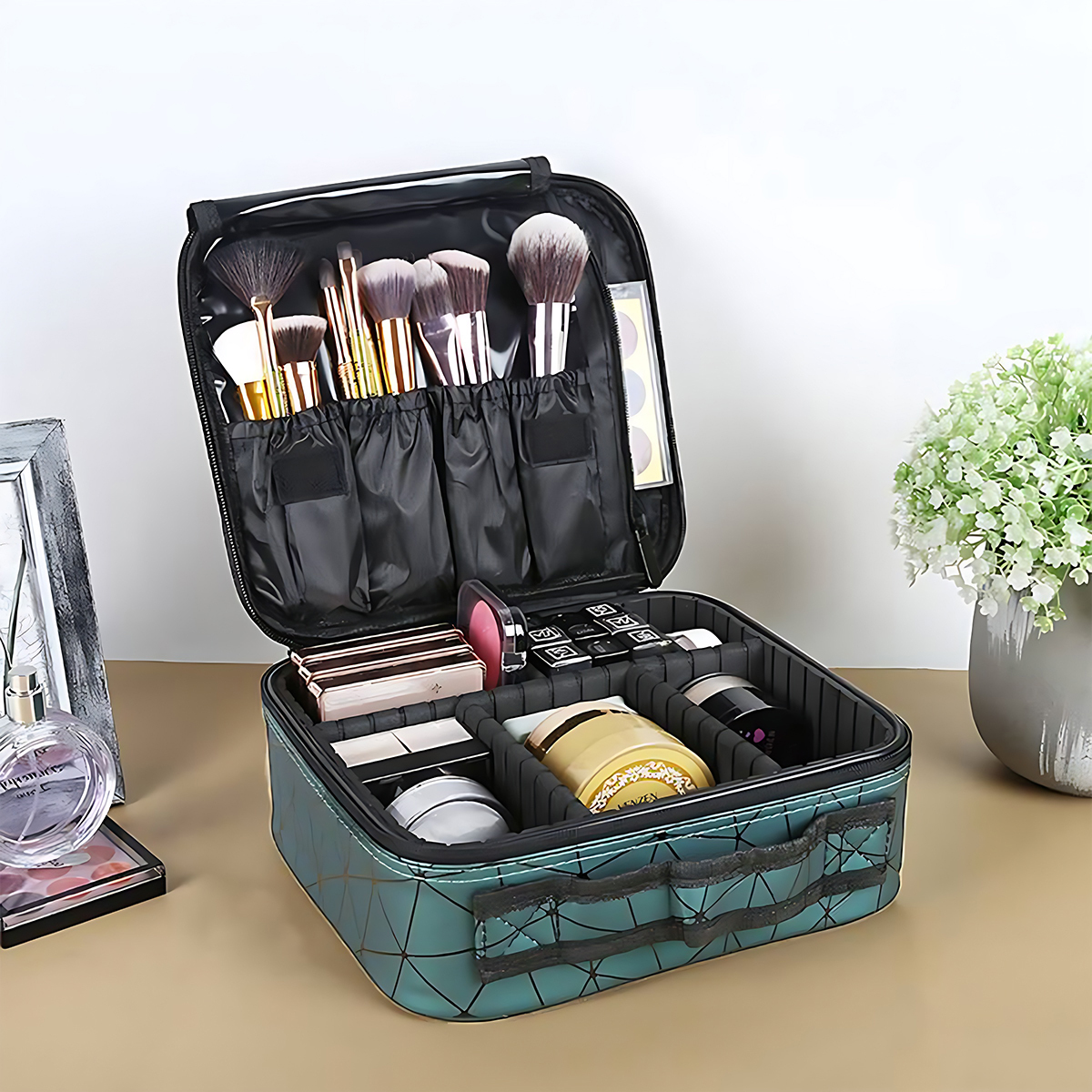 Offener tealfarbener Schminkkoffer mit verschiedenen Pinseln, Kosmetika und einem kleinen Blumengesteck auf einer beigen Oberfläche. Links ein Spiegel.