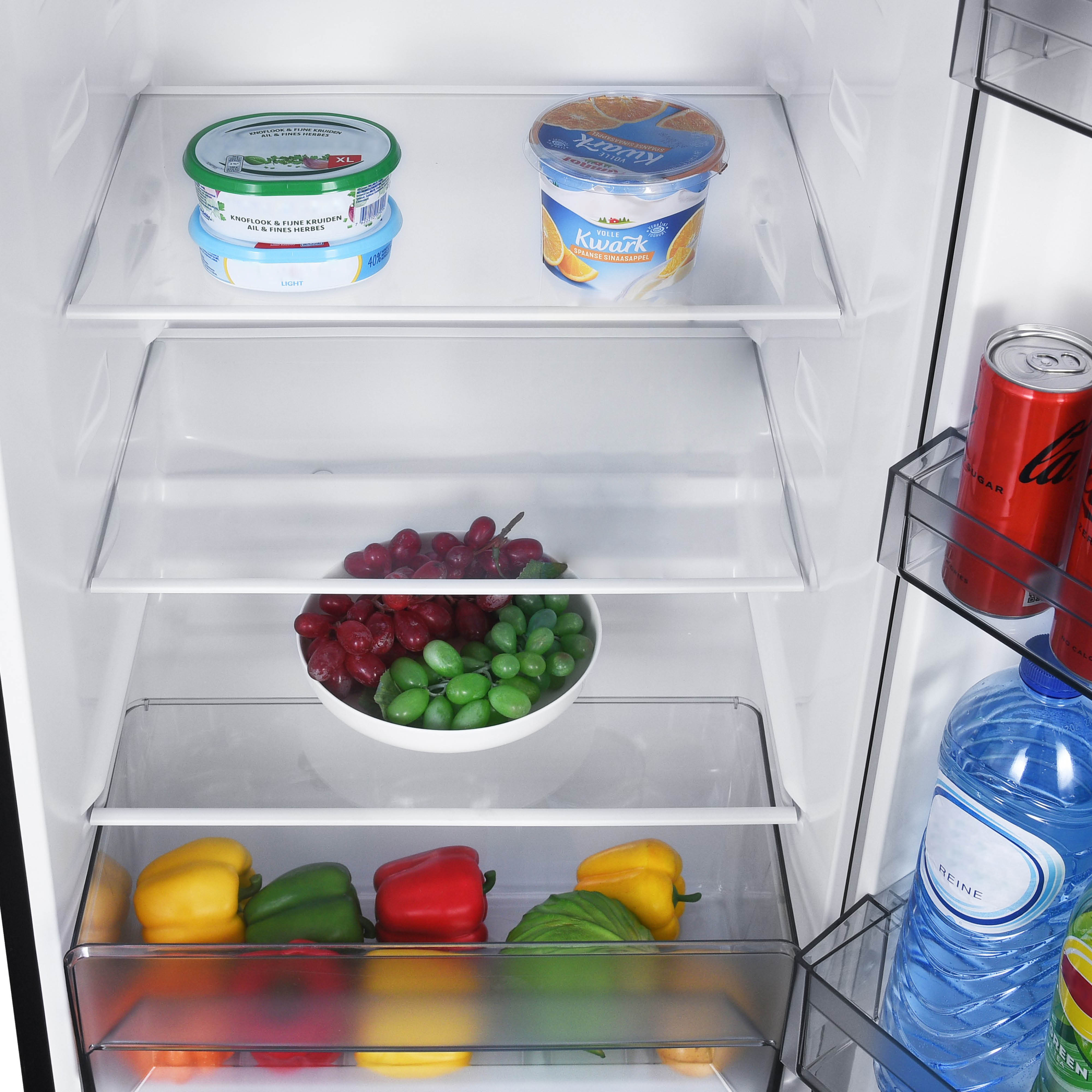 A refrigerator interior with food items on shelves and in the bottom drawer: peppers, grapes, and yogurt.