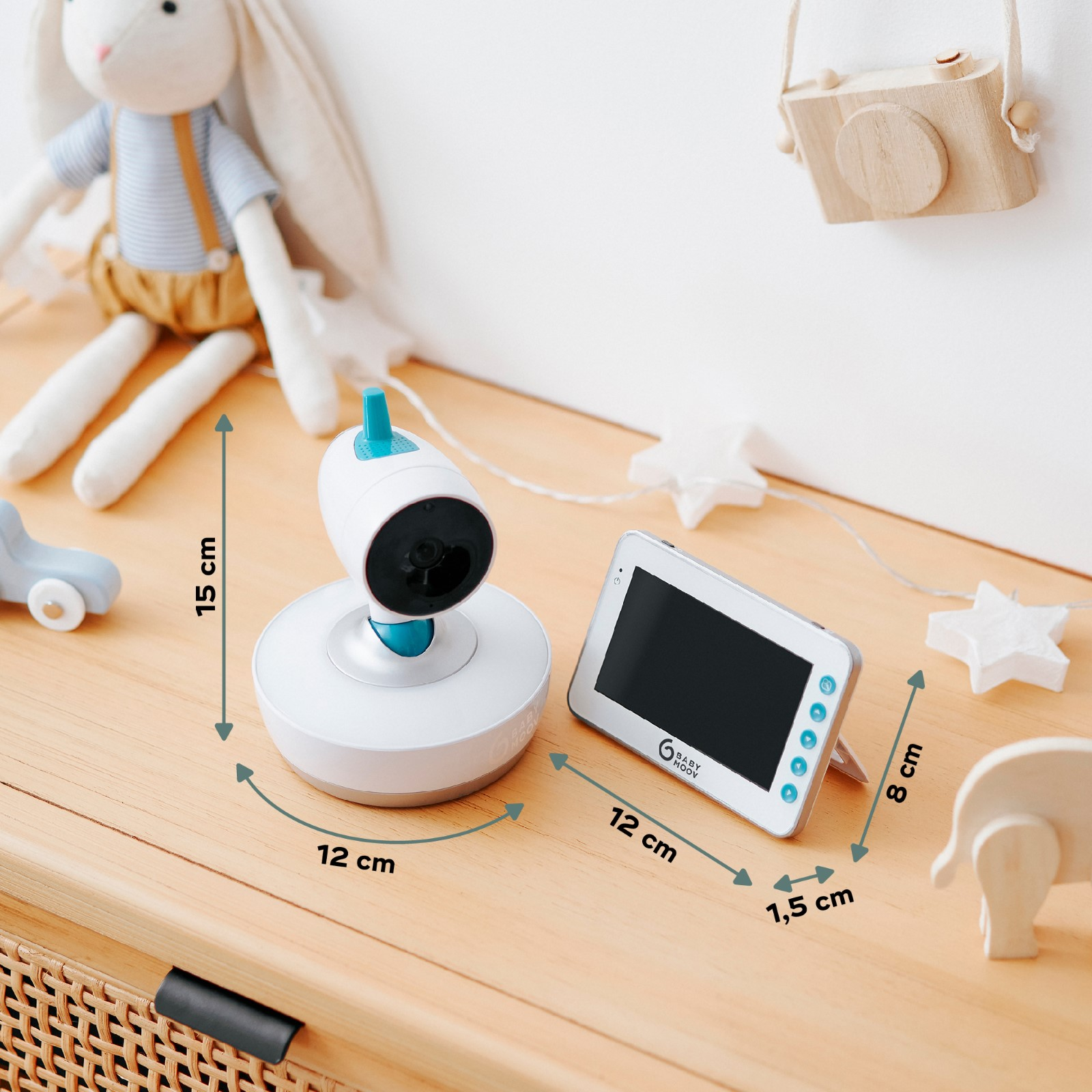 Babyphone mit Kamera und Bildschirm auf Holzoberfläche. Spielzeugkaninchen und Holzkamera im Hintergrund.