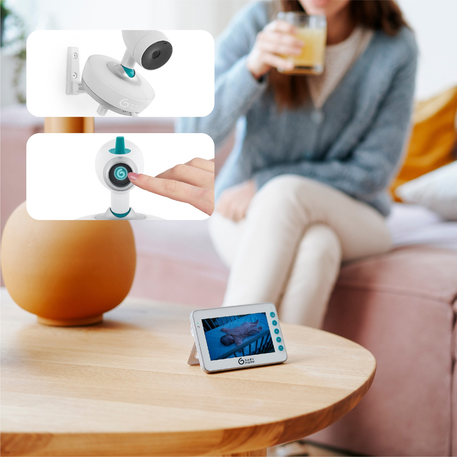 Ein Babyphone auf einem Tisch. Eine Frau hält ein Glas Saft. Der Monitor zeigt ein schlafendes Baby.
