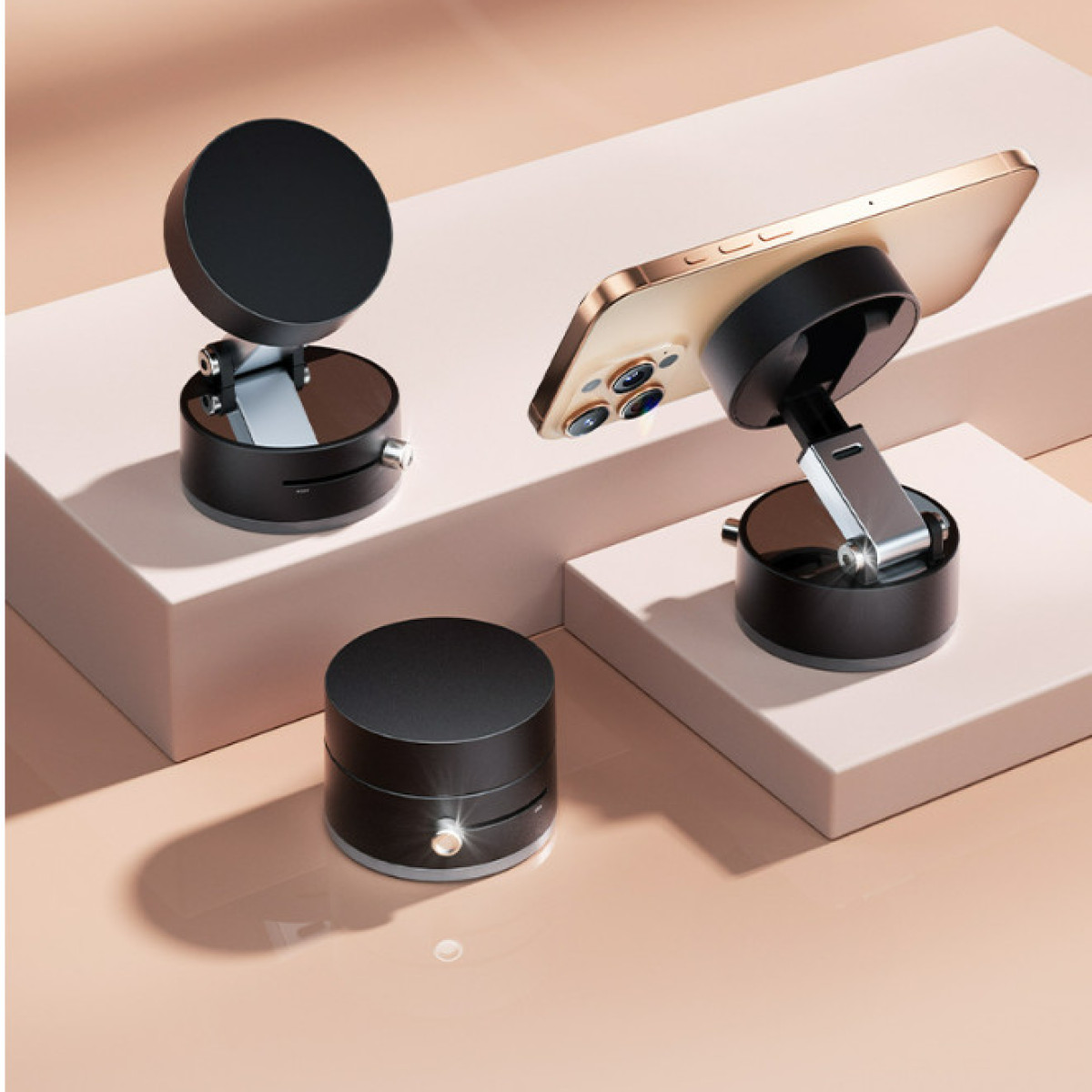 Czarne stojaki na telefon z dołączonym złotym telefonem. Stojaki znajdują się na brzoskwiniowym tle z białym kwadratem. Obecny jest również czarny cylinder.