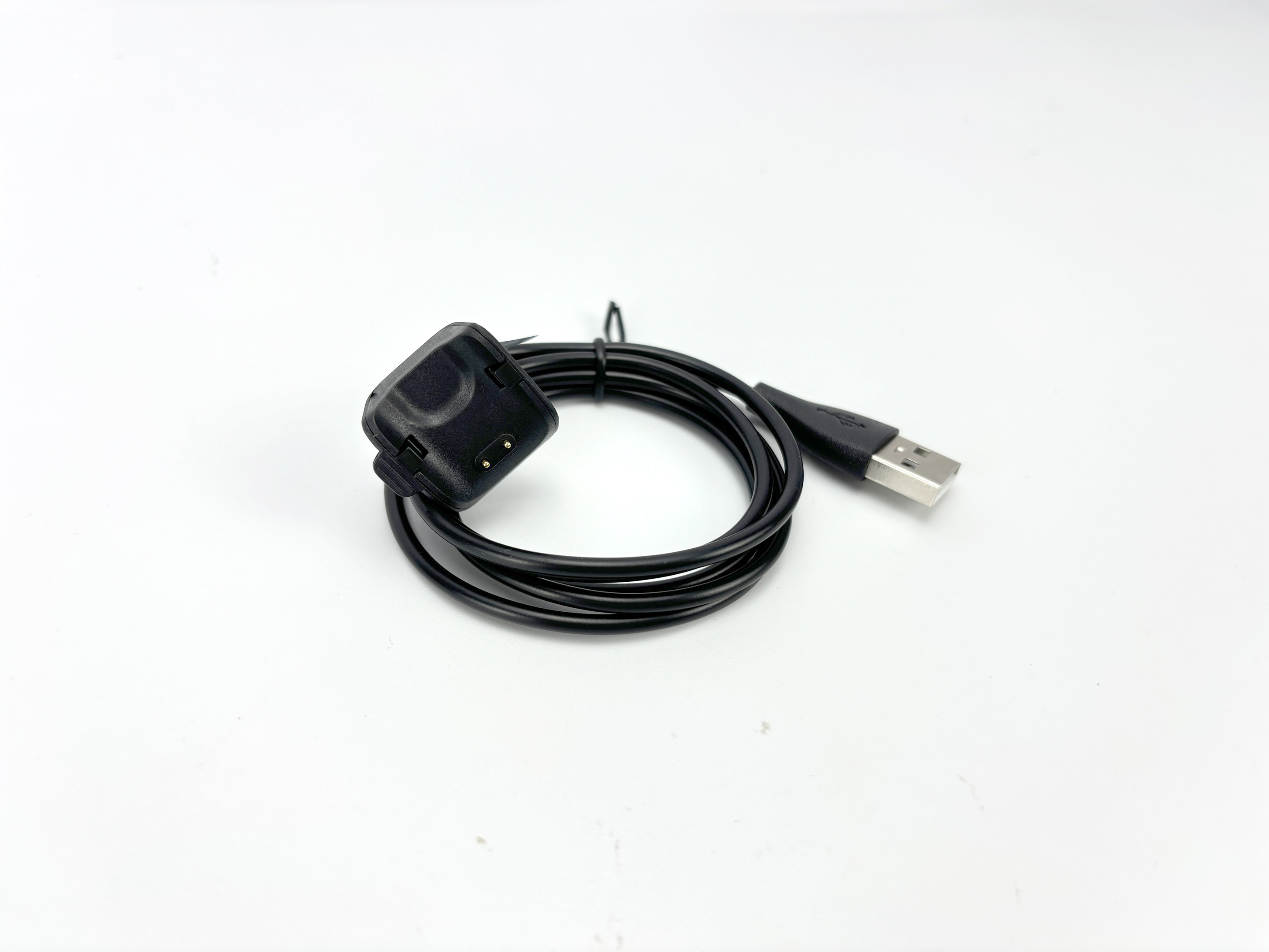 Czarna ładowarka do smartwatcha z kablem USB na białym tle. Ładowarka po lewej, USB po prawej.