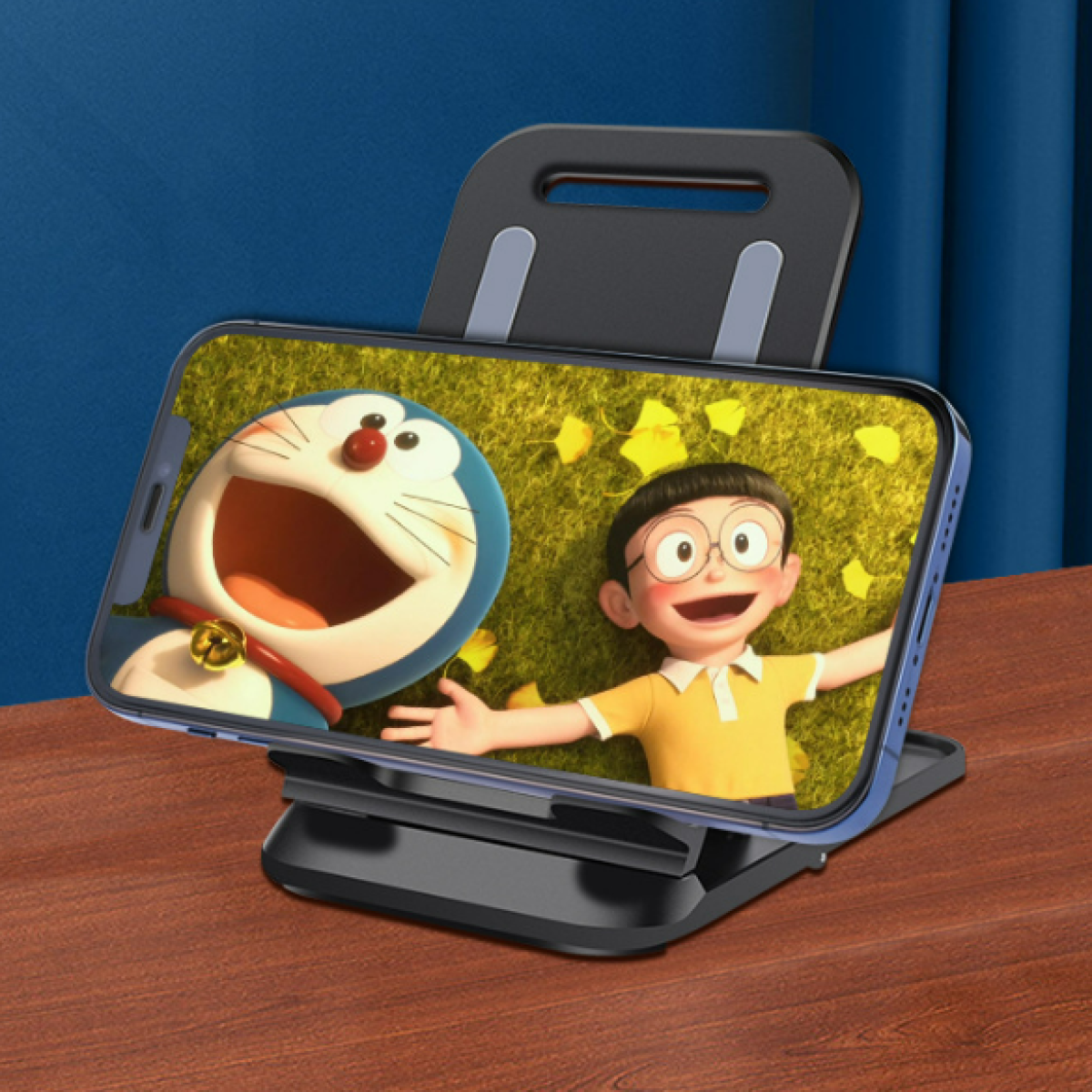 Telefon wyświetlający scenę z kreskówki Doraemon i Nobita na stojaku. Stojak jest czarny, a tło to drewniany stół.