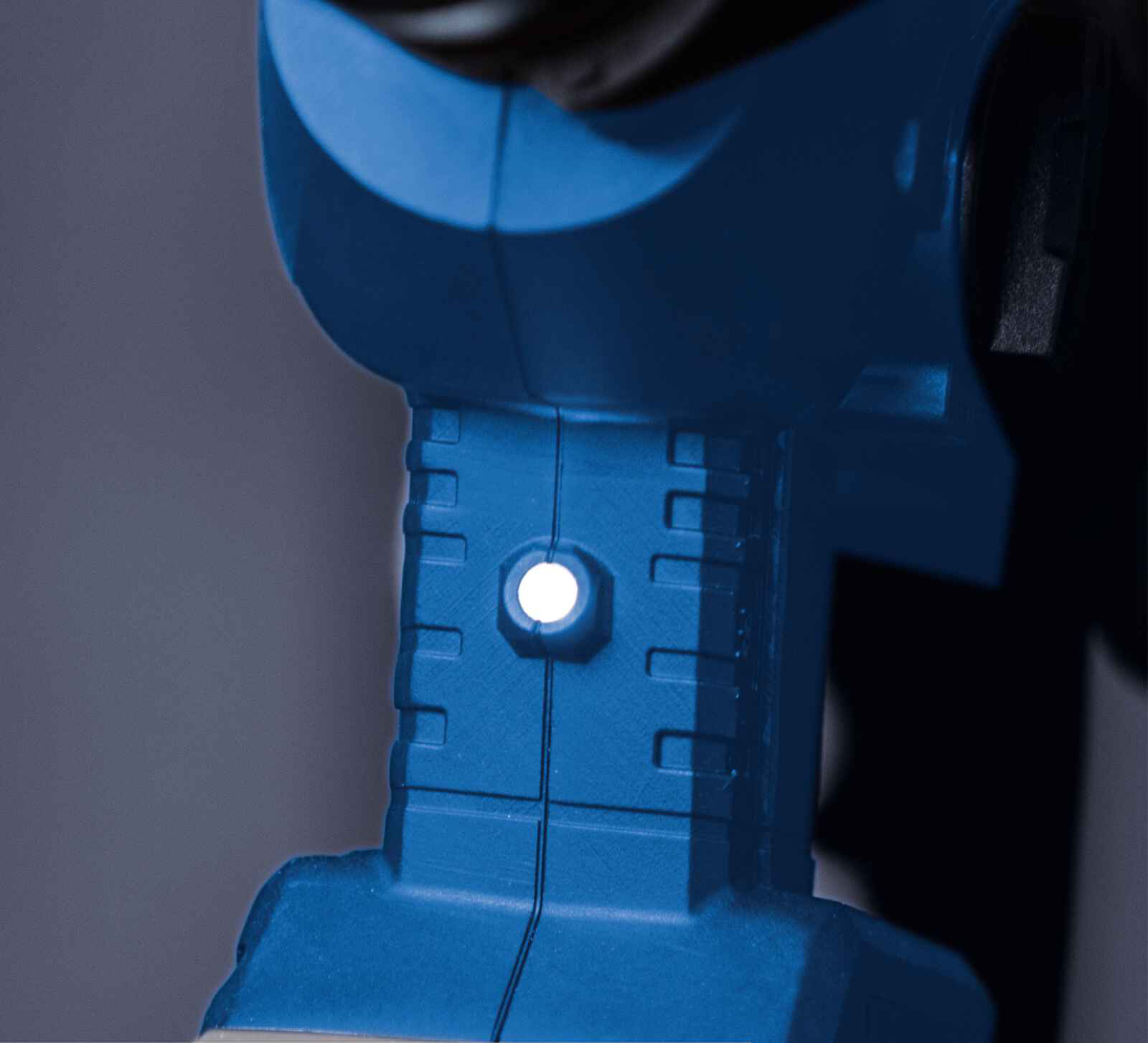 Nahaufnahme eines blauen Elektrowerkzeugs. Ein helles weißes Licht ist eingeschaltet, umgeben von einem rechteckigen Rahmen. Dunkler Hintergrund.